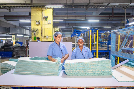 Workers are in a textile factory, processing materials.