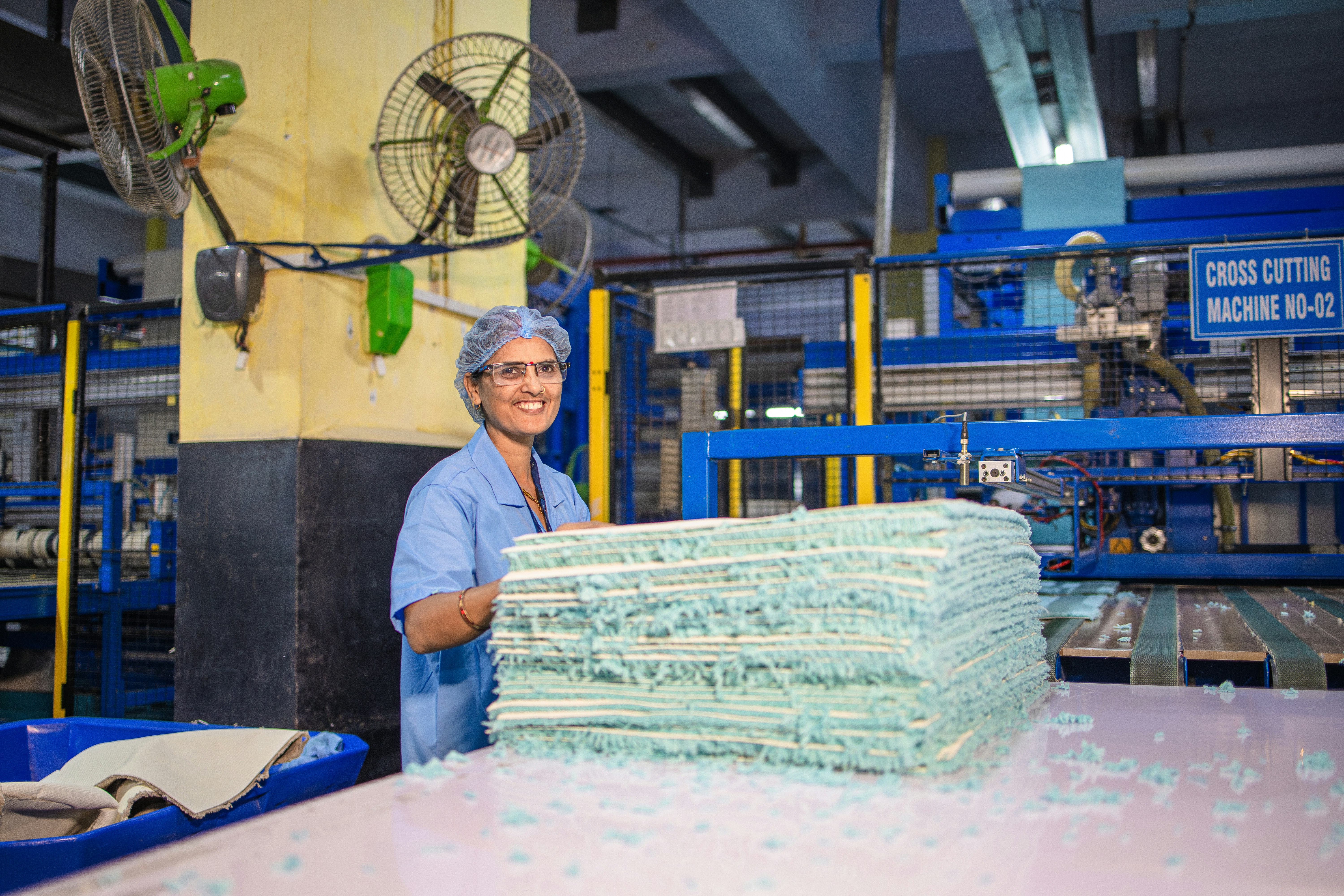 A smiling woman works in a foam factory.
