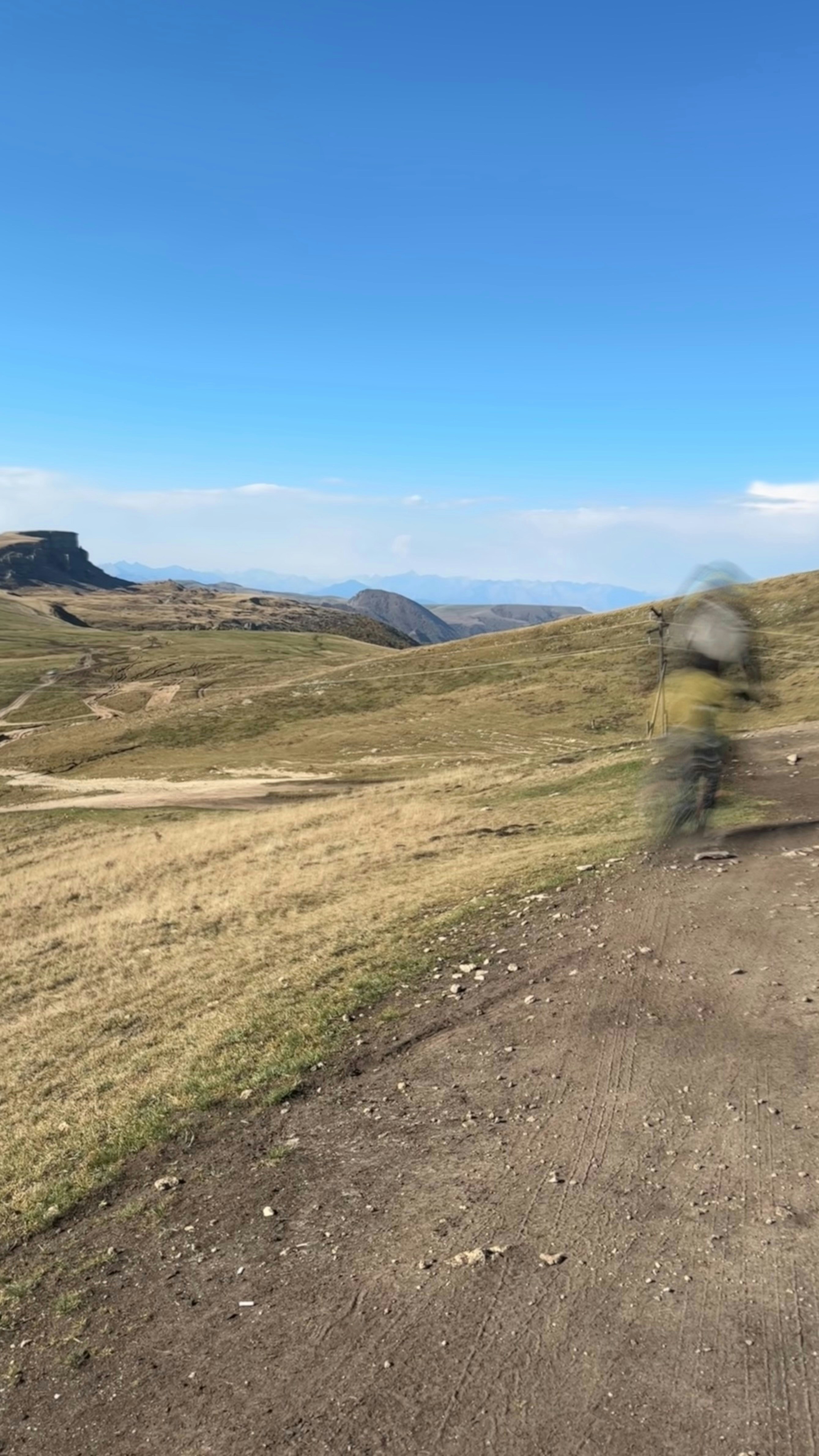 A cyclist rides across a mountain landscape.
