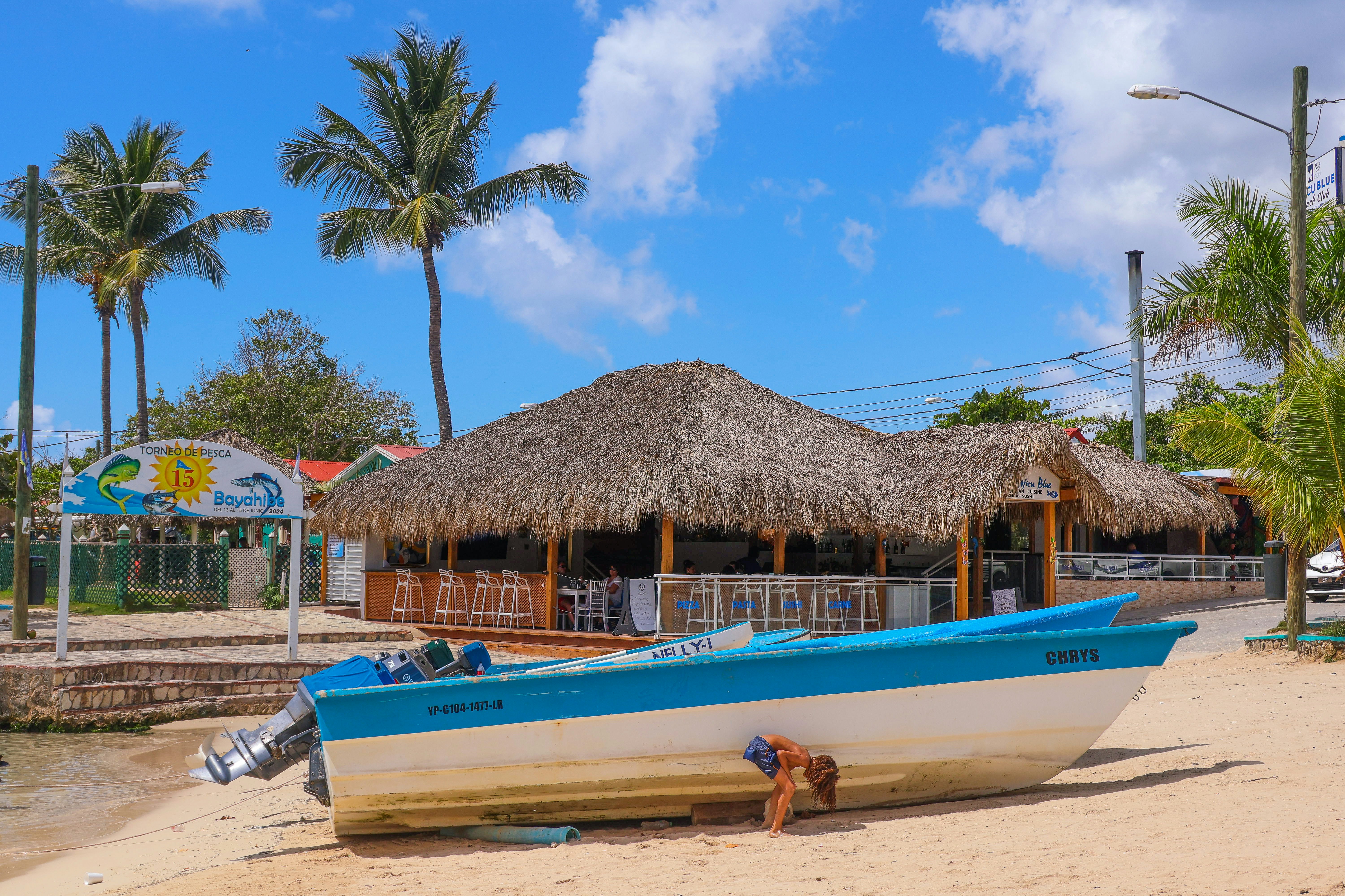 Chiringuito y barco bajo un cielo soleado.