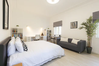 A bright bedroom features a bed and workspace.