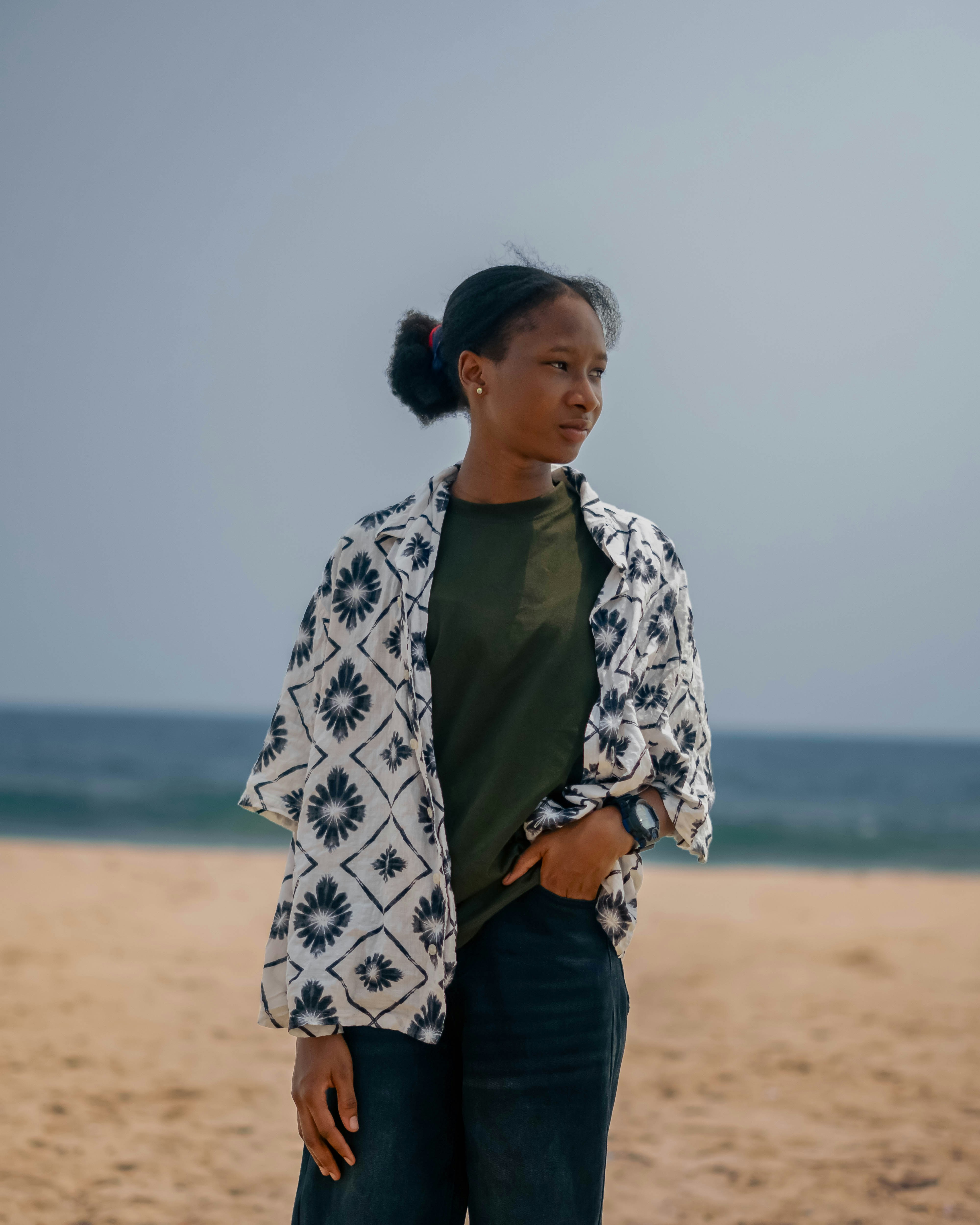 Woman poses on the beach, looking contemplative.