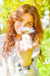 A beautiful woman enjoys a daisy.