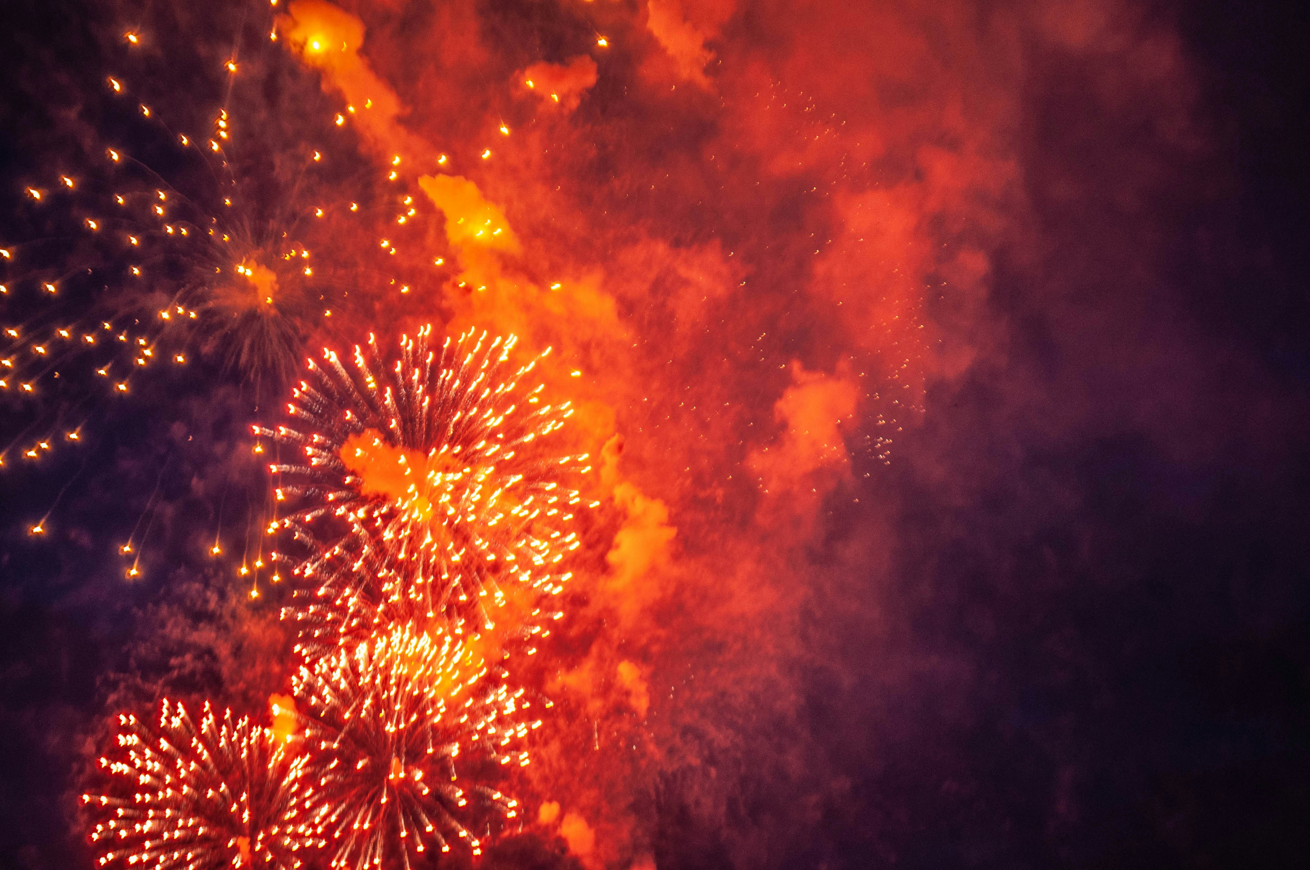 Fireworks light up a dark, smoky sky.