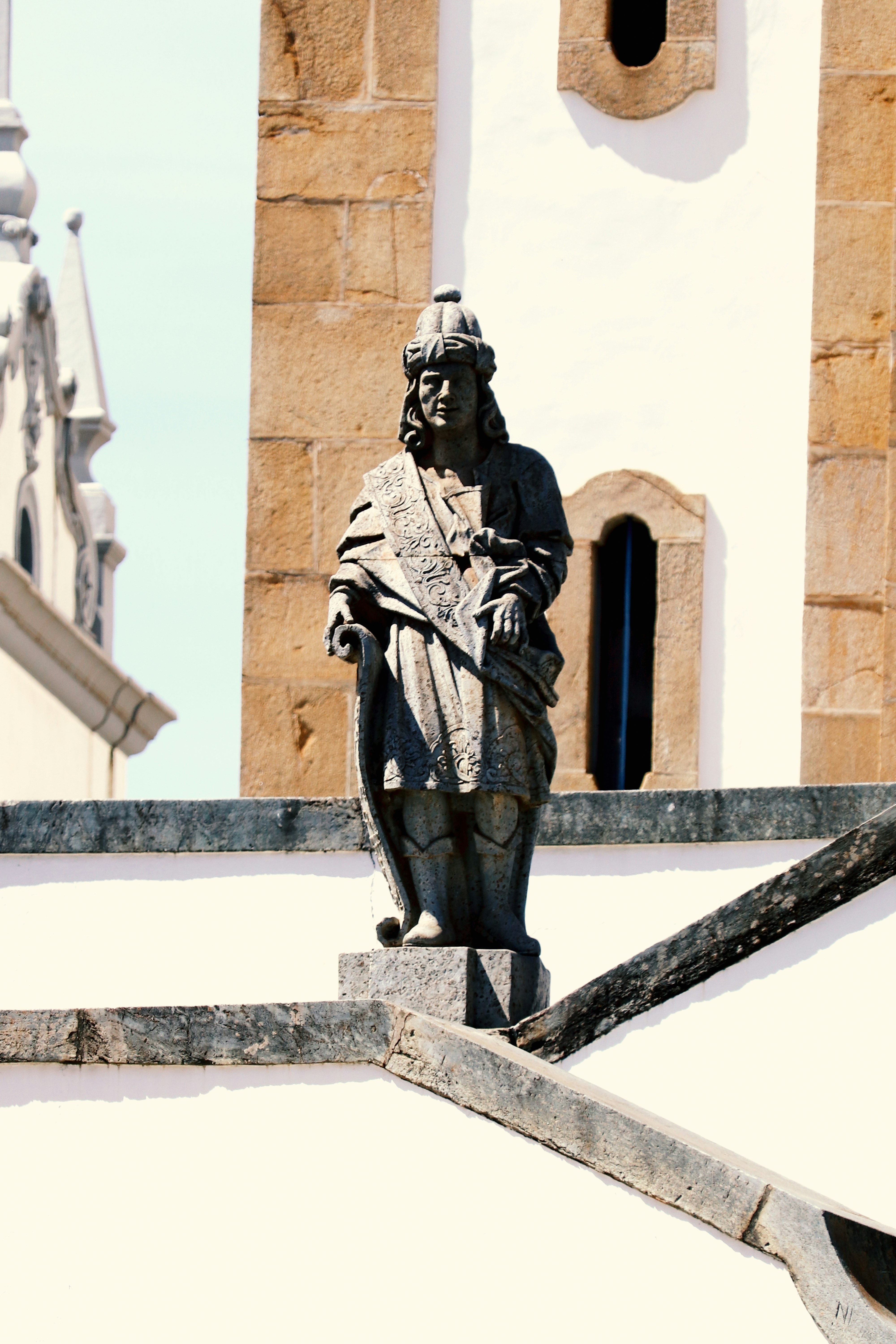 Stone statue stands atop a building's steps.