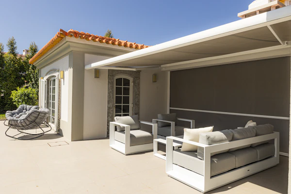 Moderne zonwering met uitgeschoven knikarmscherm en screen boven een terras bij een woning