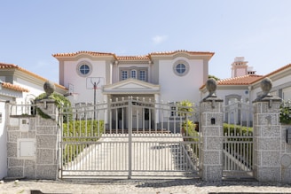 A luxurious mansion with a large front gate.
