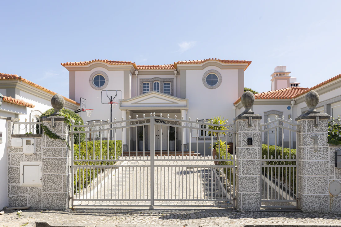 White automatic double swing driveway gates with stone pillars at a luxury home entrance