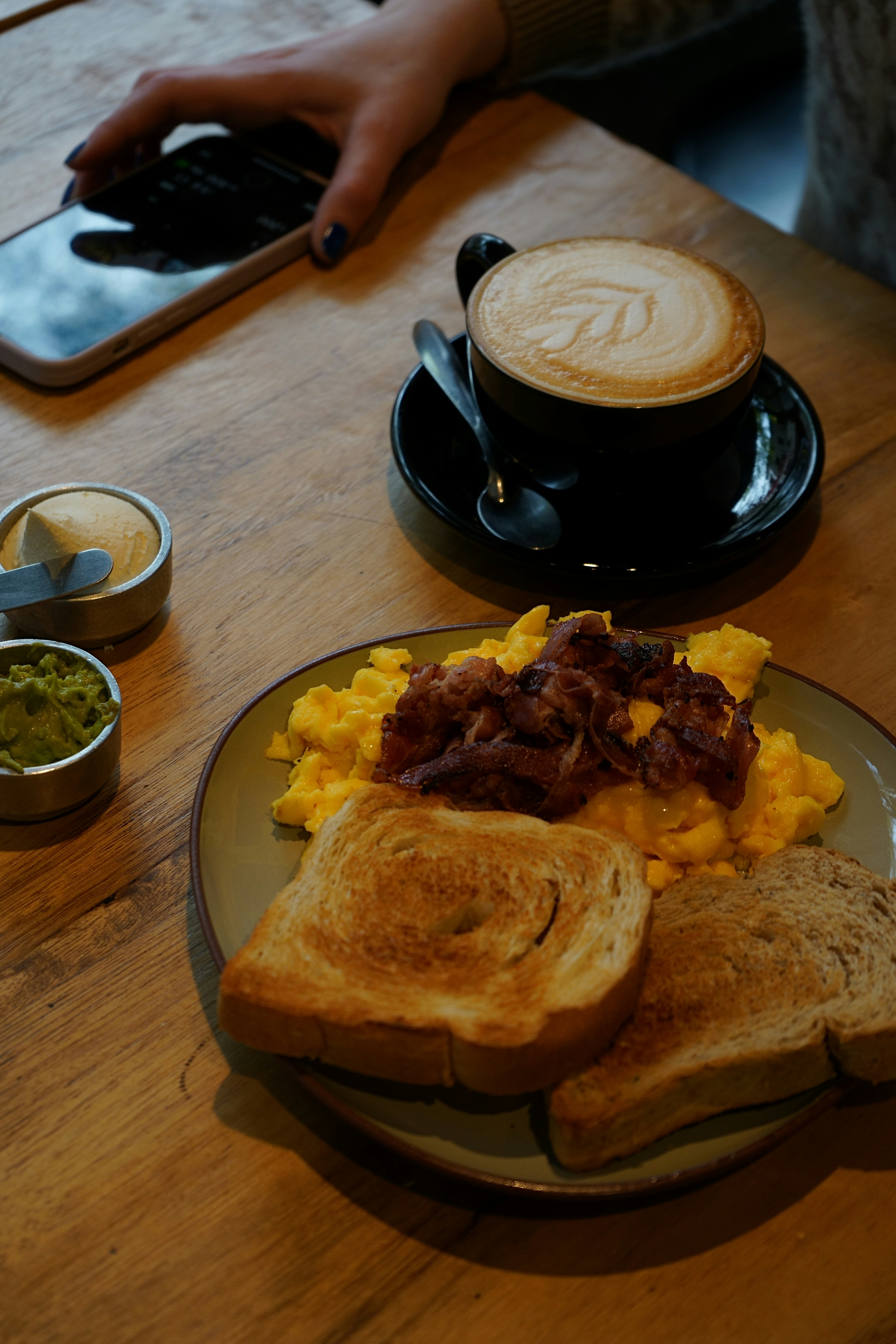 A white plate filled with scrambled eggs, crispy bacon, and buttered sourdough toast