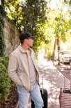 A man looks off, standing with luggage.