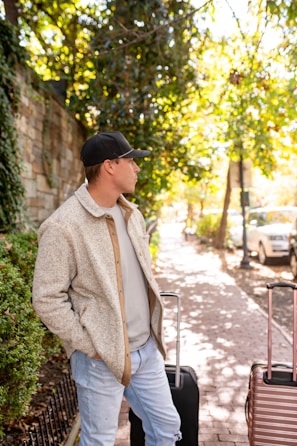 A man looks off, standing with luggage.