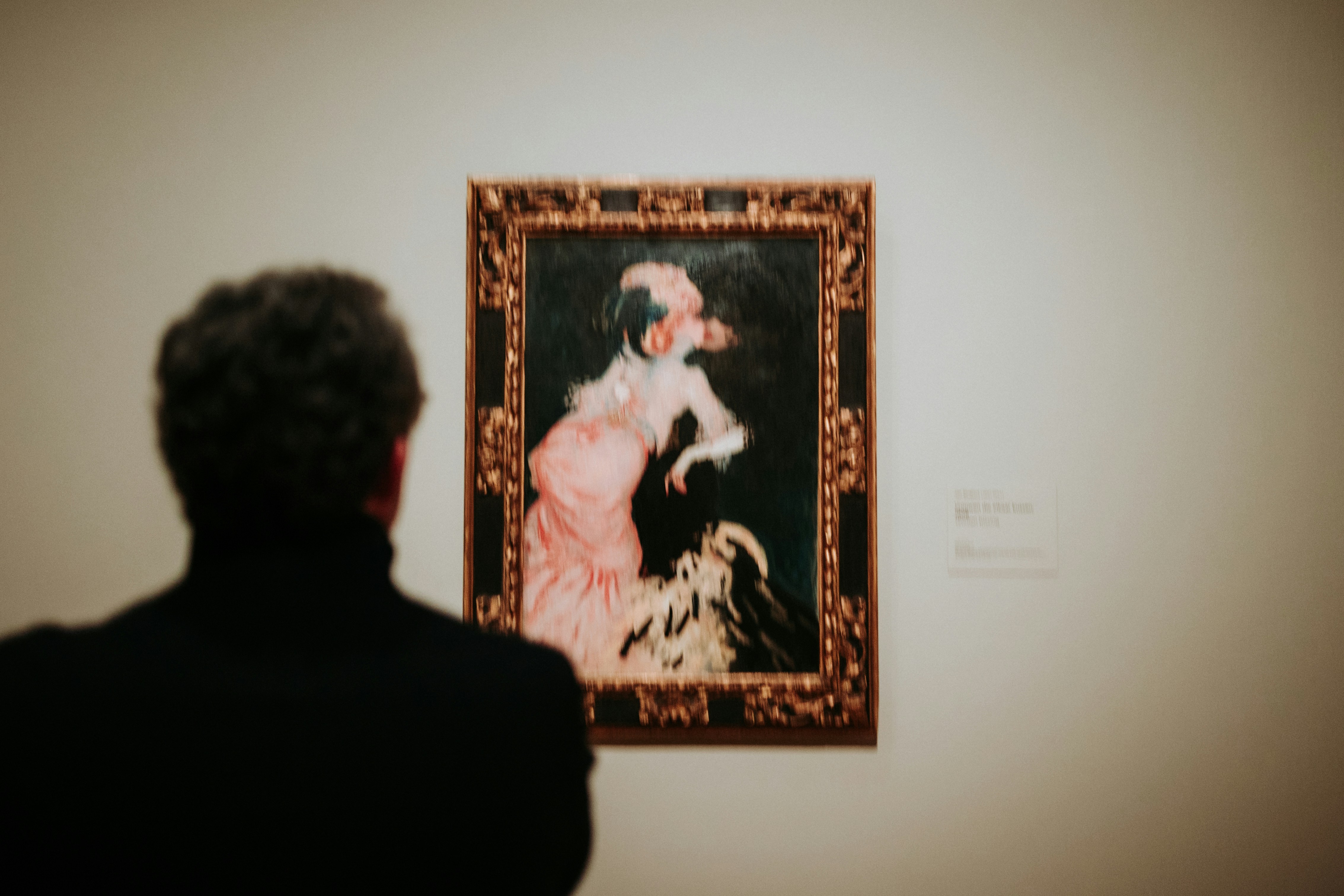 ギャラリーで華やかな絵画を賞賛する男性。