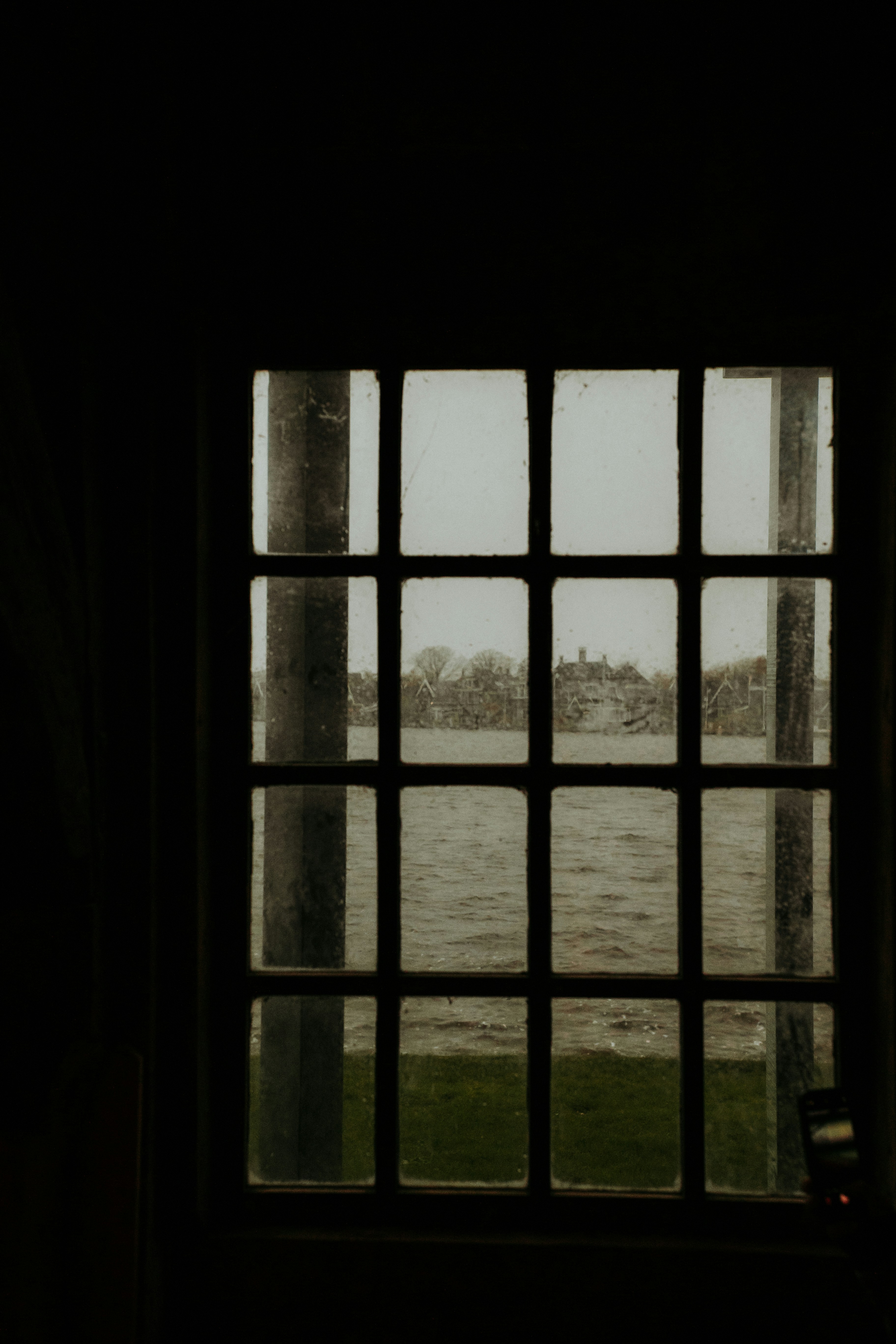 A gridded window frames an overcast waterscape.