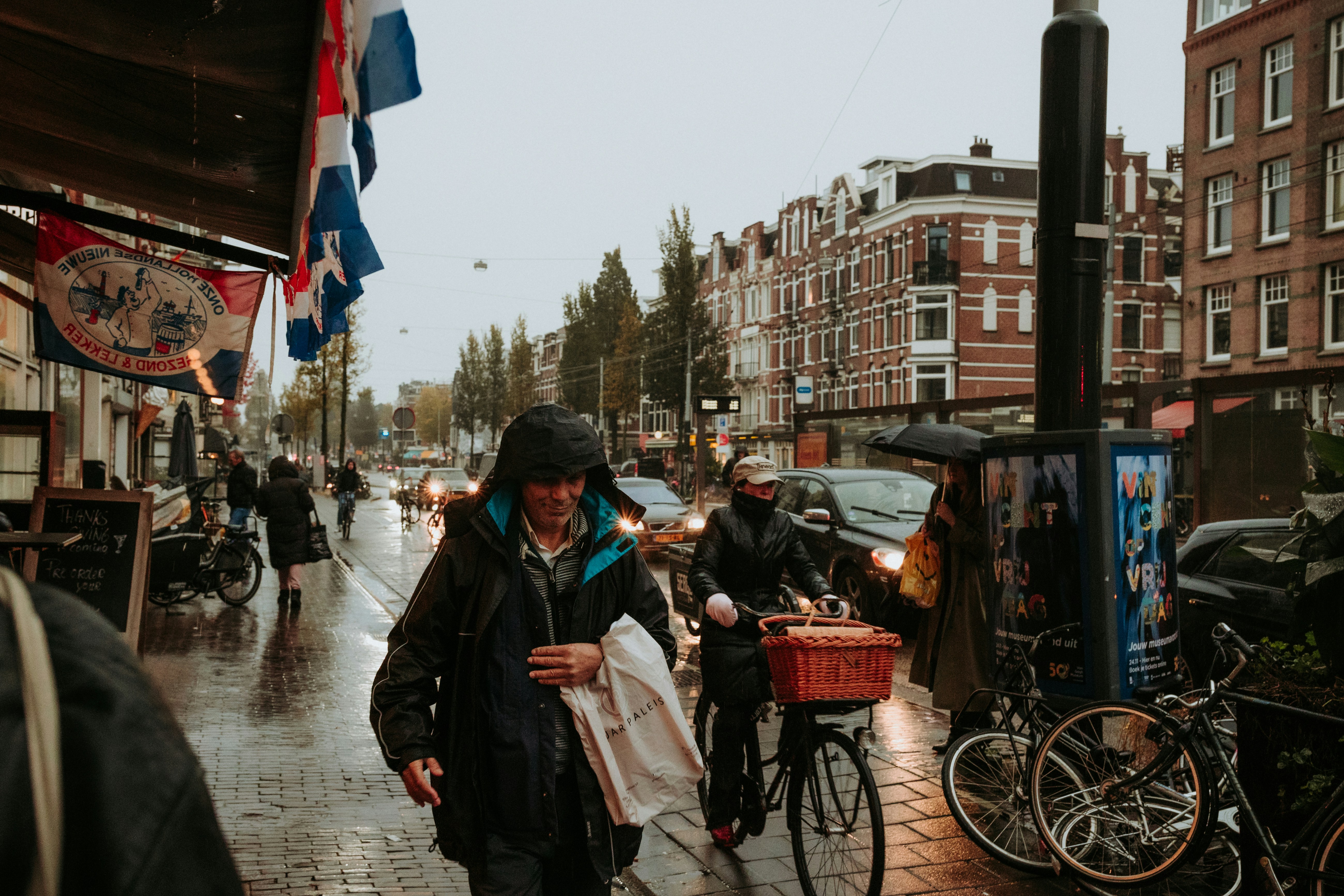 People walk and bike on a rainy street.
