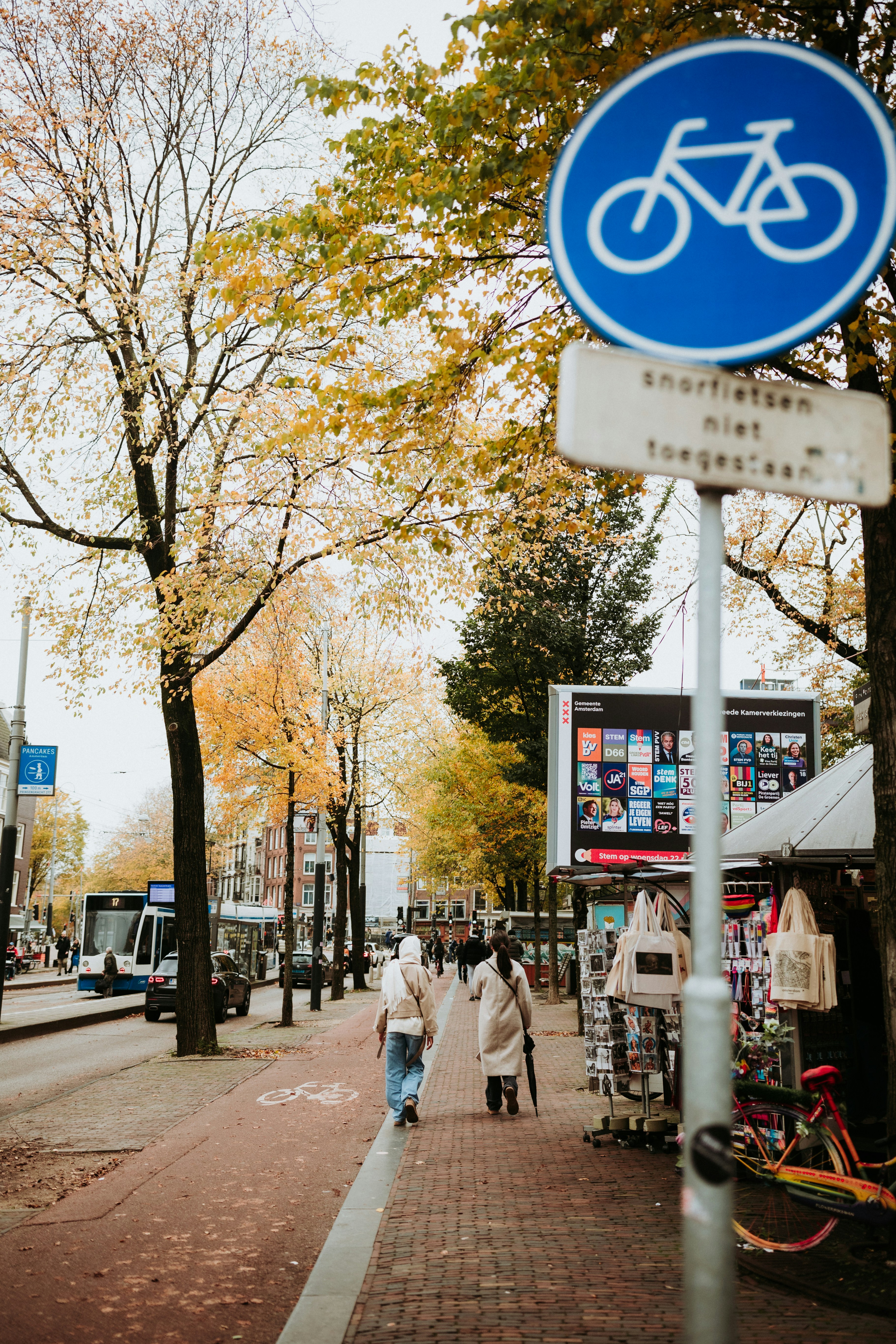 People walk along a bike path near a sign.