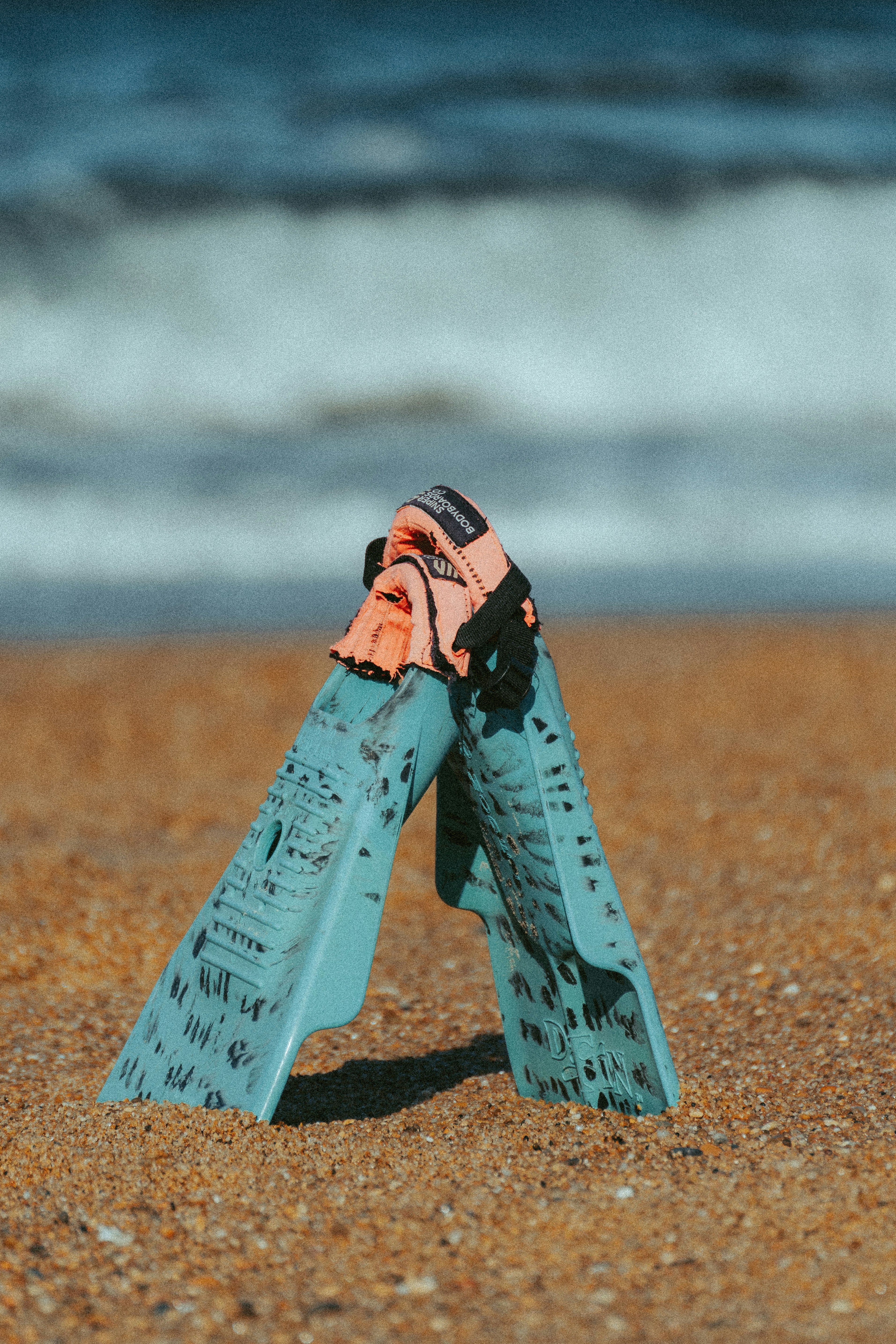 Fins and socks on a sandy beach.