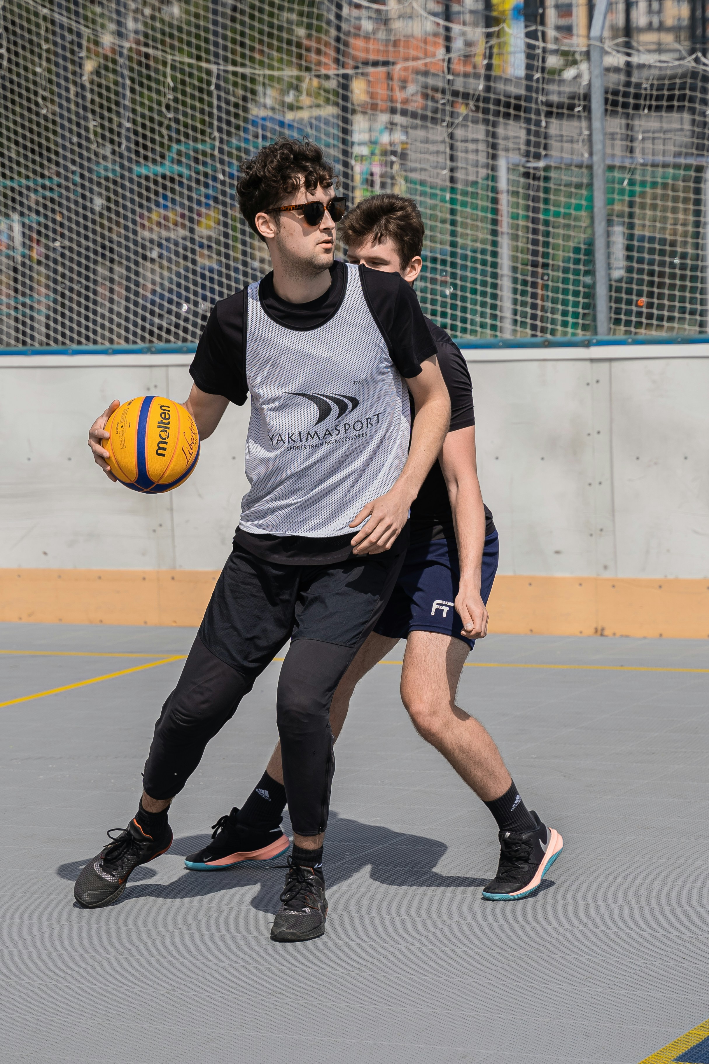 Two men are playing basketball on an outdoor court.