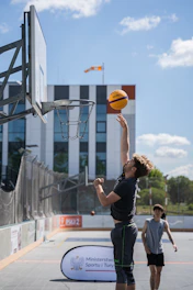 A man shoots a basketball at an outdoor court.