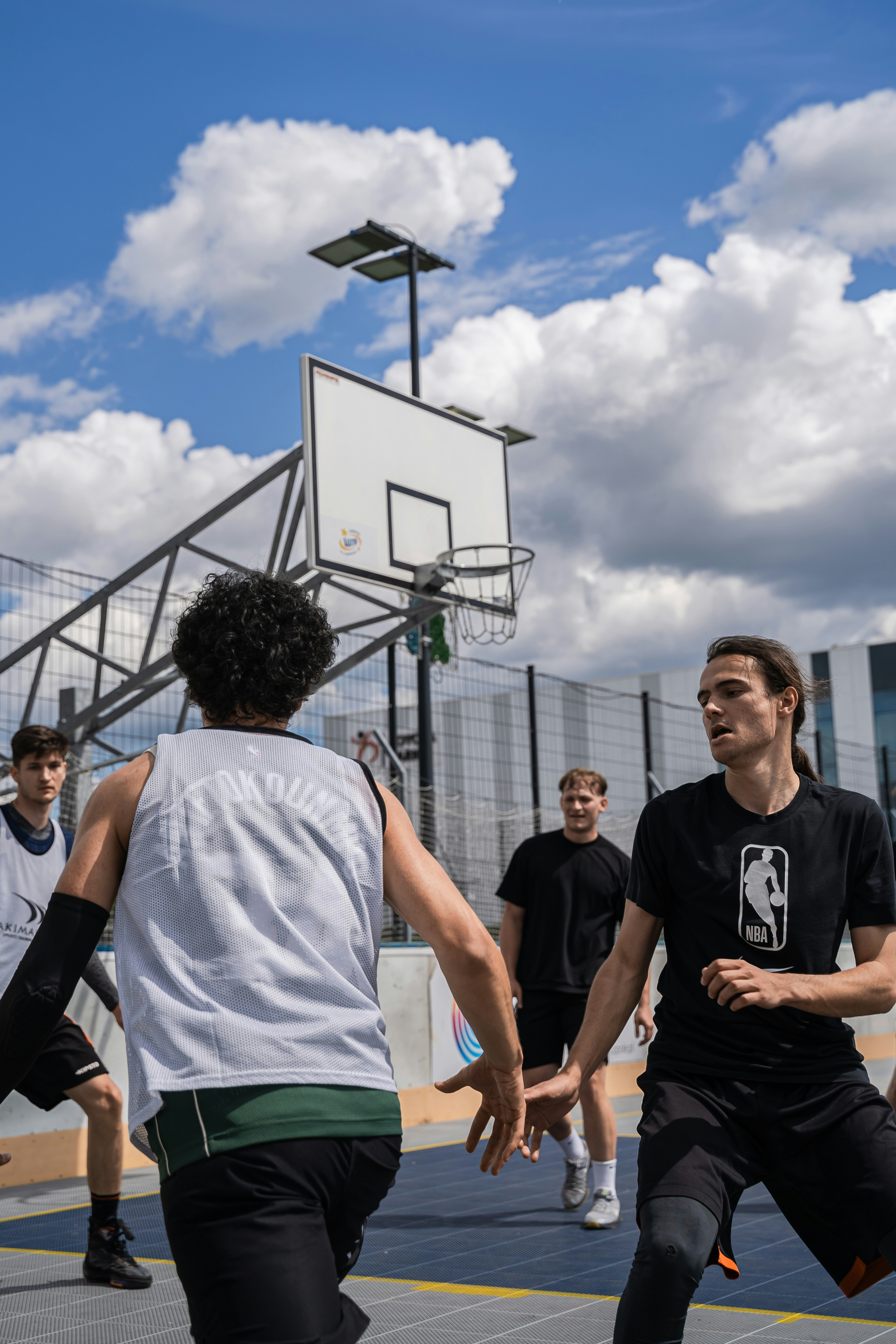 People are playing basketball on a sunny day.
