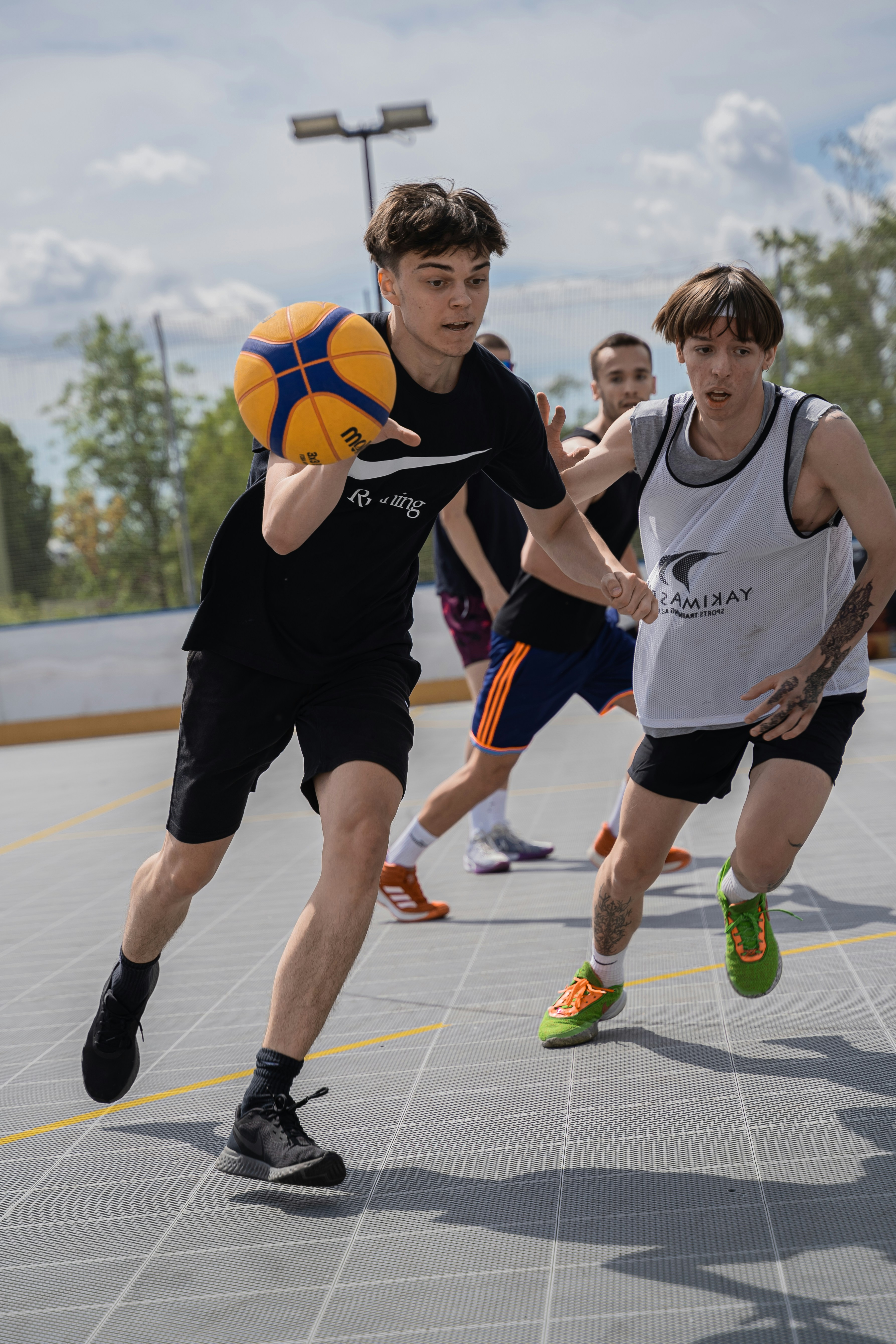 Boys play a game of basketball outdoors.