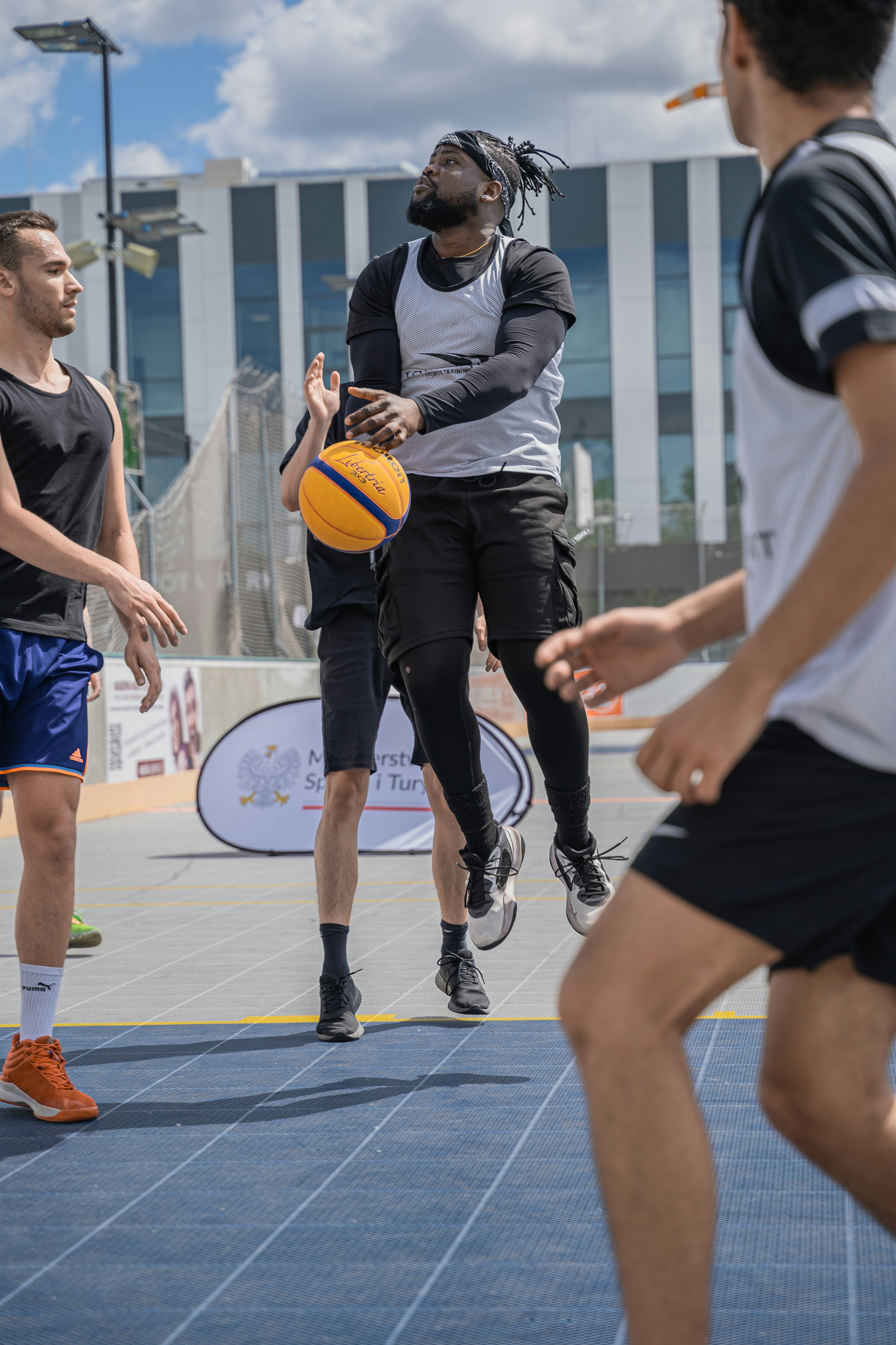 Men are playing basketball outside on a court.