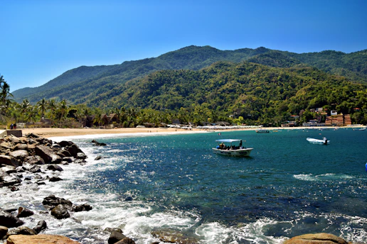Beautiful beach scene with mountains and boats.