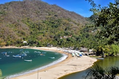 A beautiful beach scene with boats and mountains.