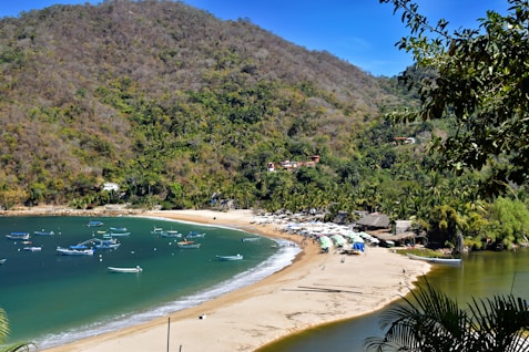 A beautiful beach scene with boats and mountains.