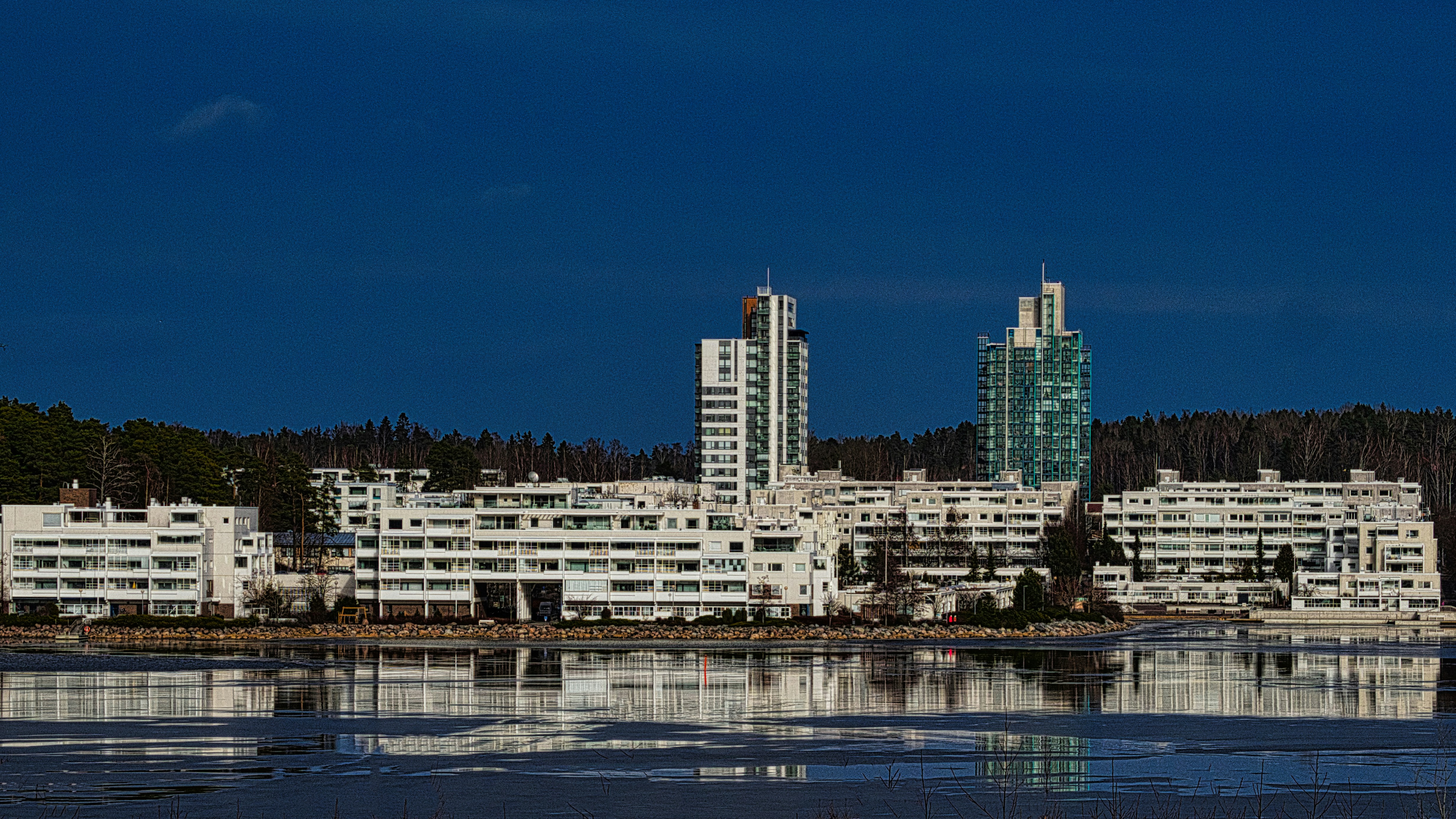 Modern white buildings stand near a body of water.