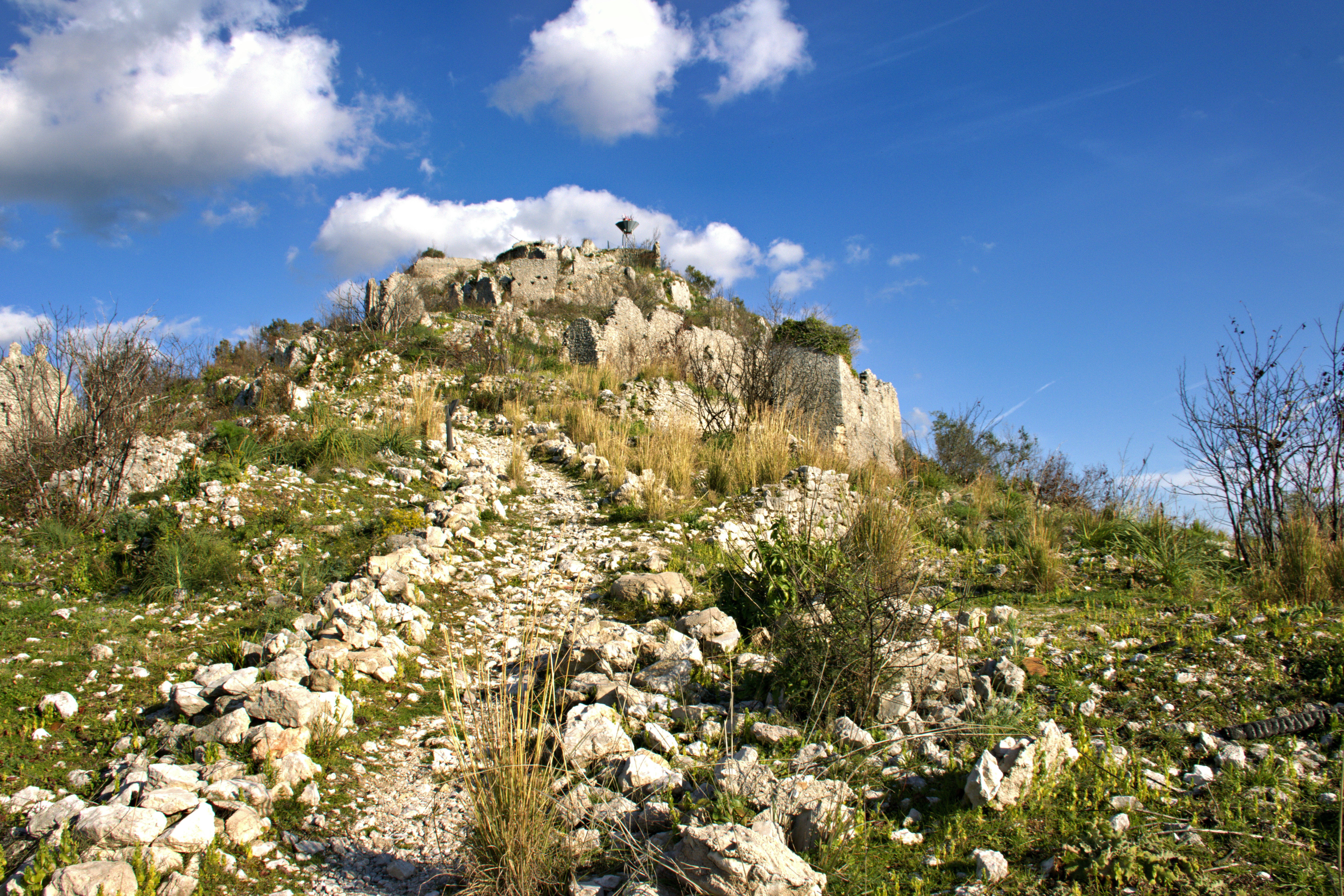 Rocky terrain with a stone structure and blue sky.