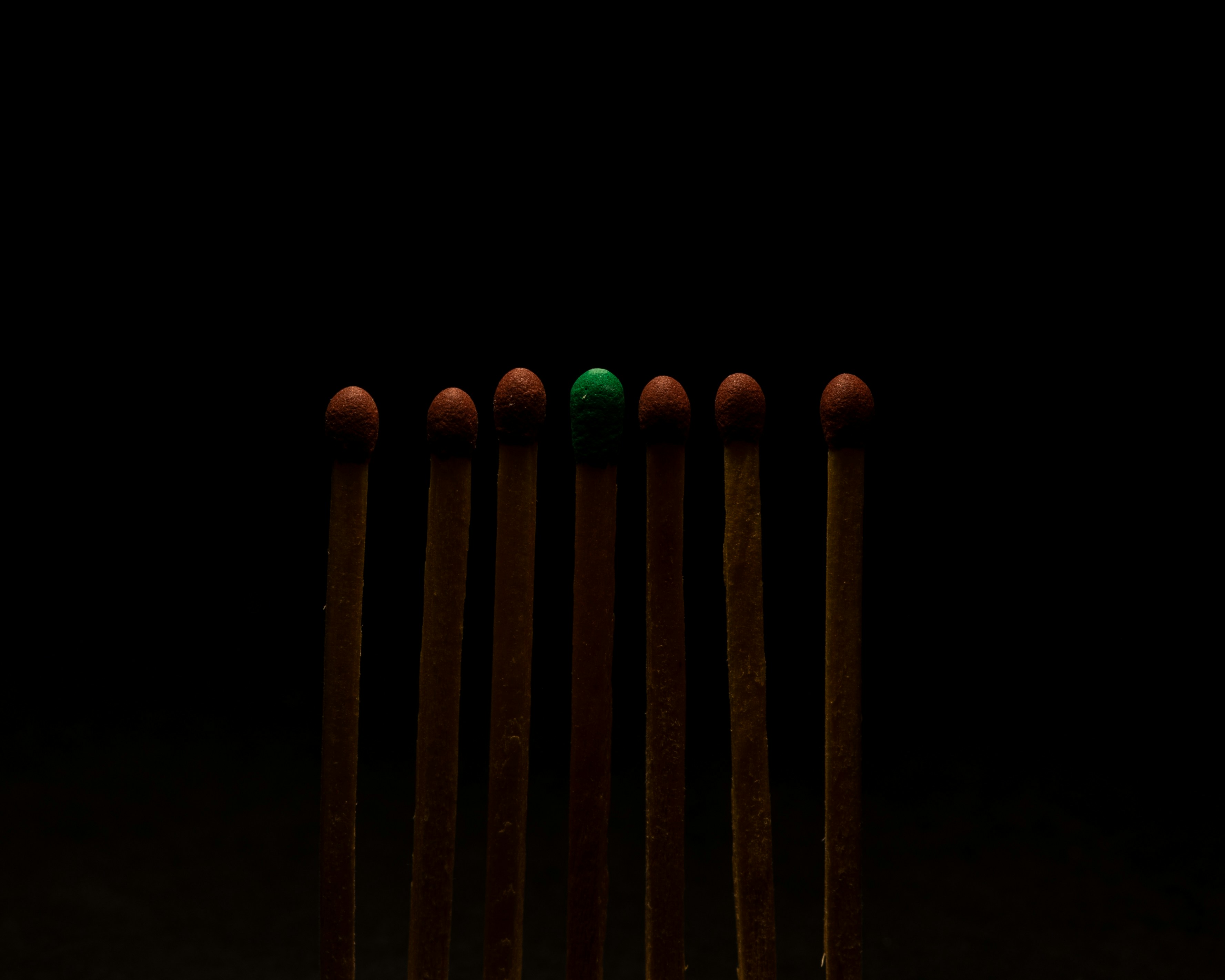 Un fósforo verde se destaca entre muchos rojos.