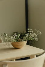 Flowers in a wooden bowl on a table.