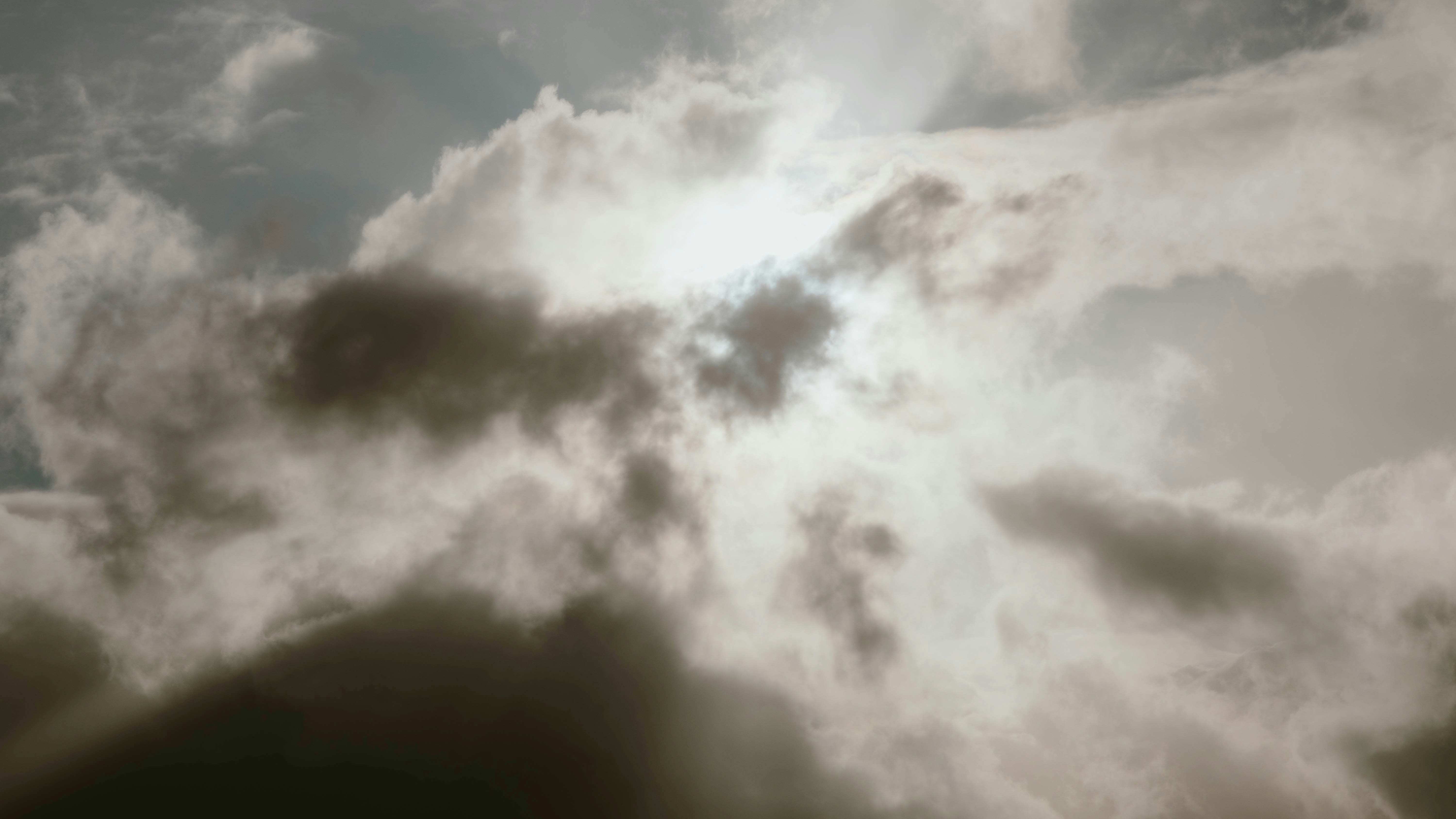 Sunlight peeks through overcast, dark clouds.