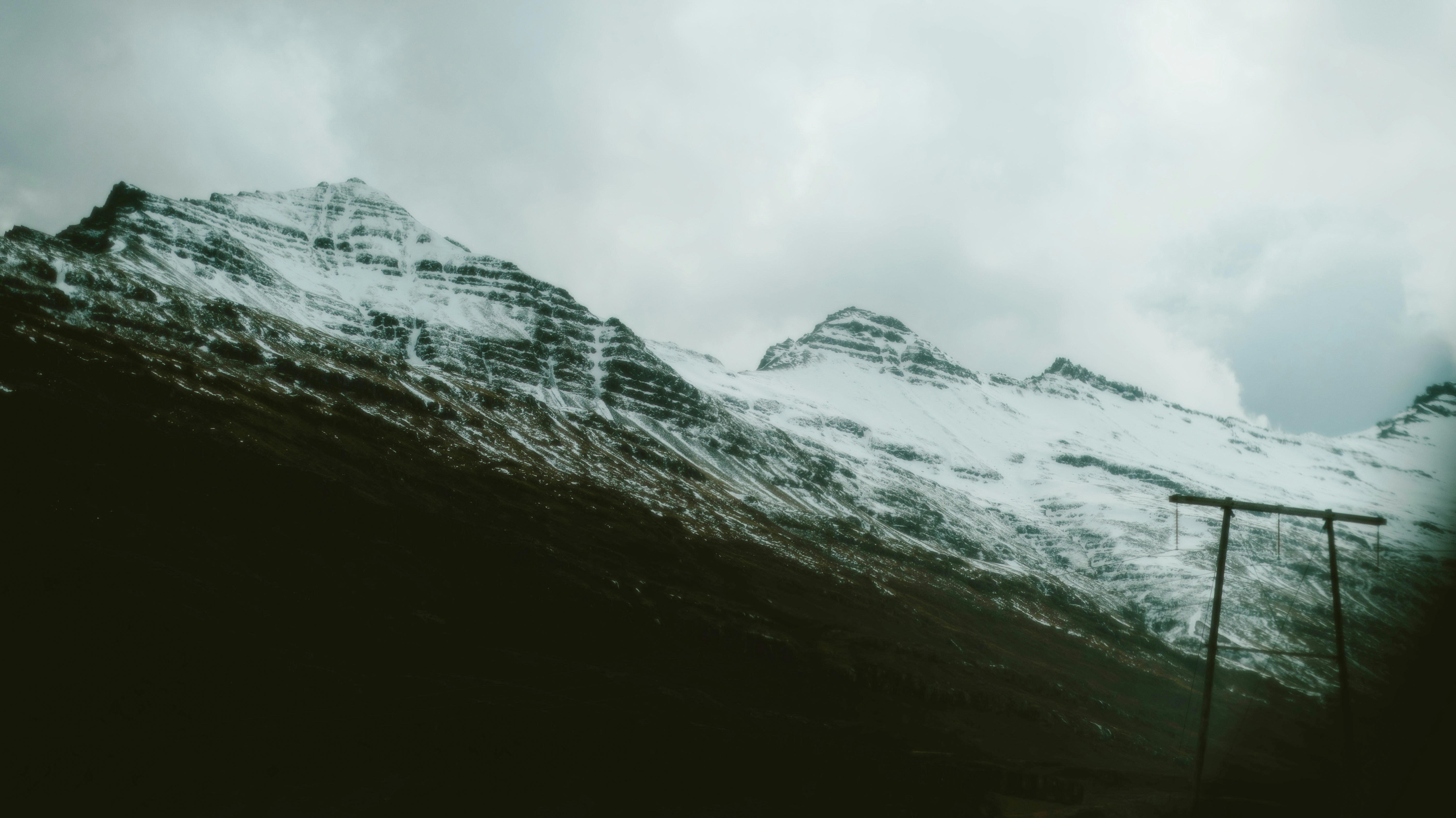 Snow-capped mountains dominate a cloudy, somber scene.