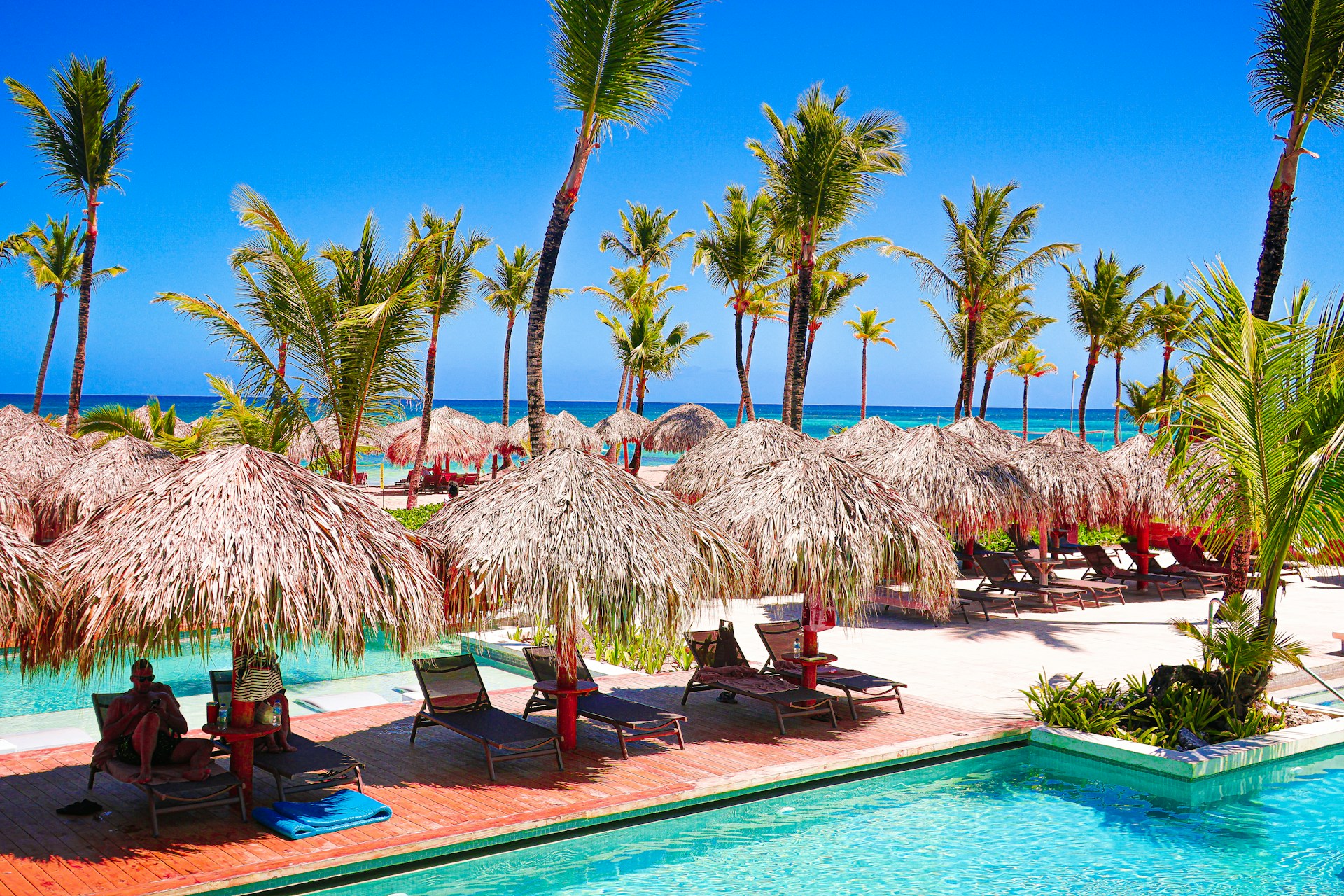 Relaxing beach resort with a pool and palm trees.