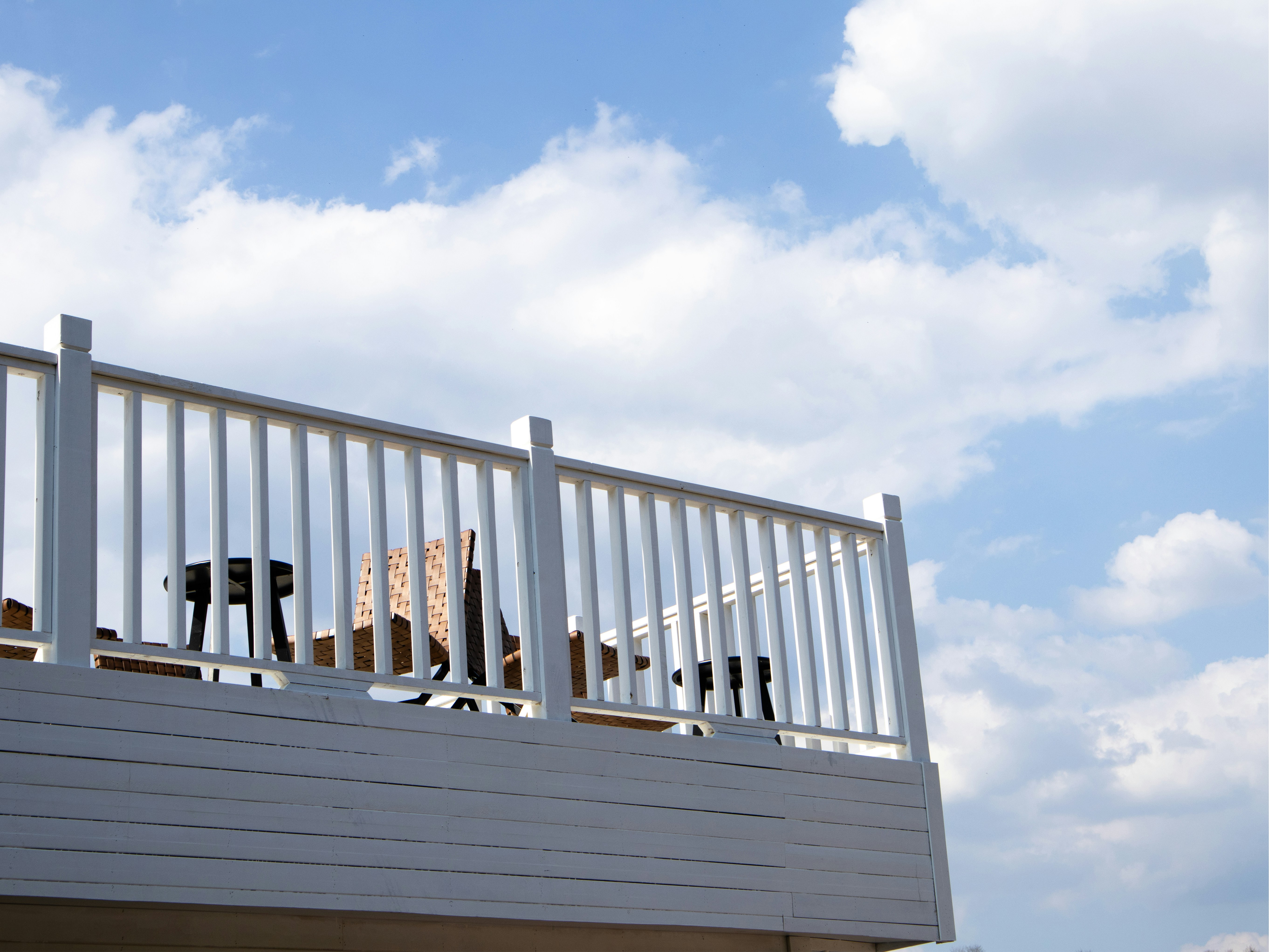 A white deck with chairs against a blue sky.