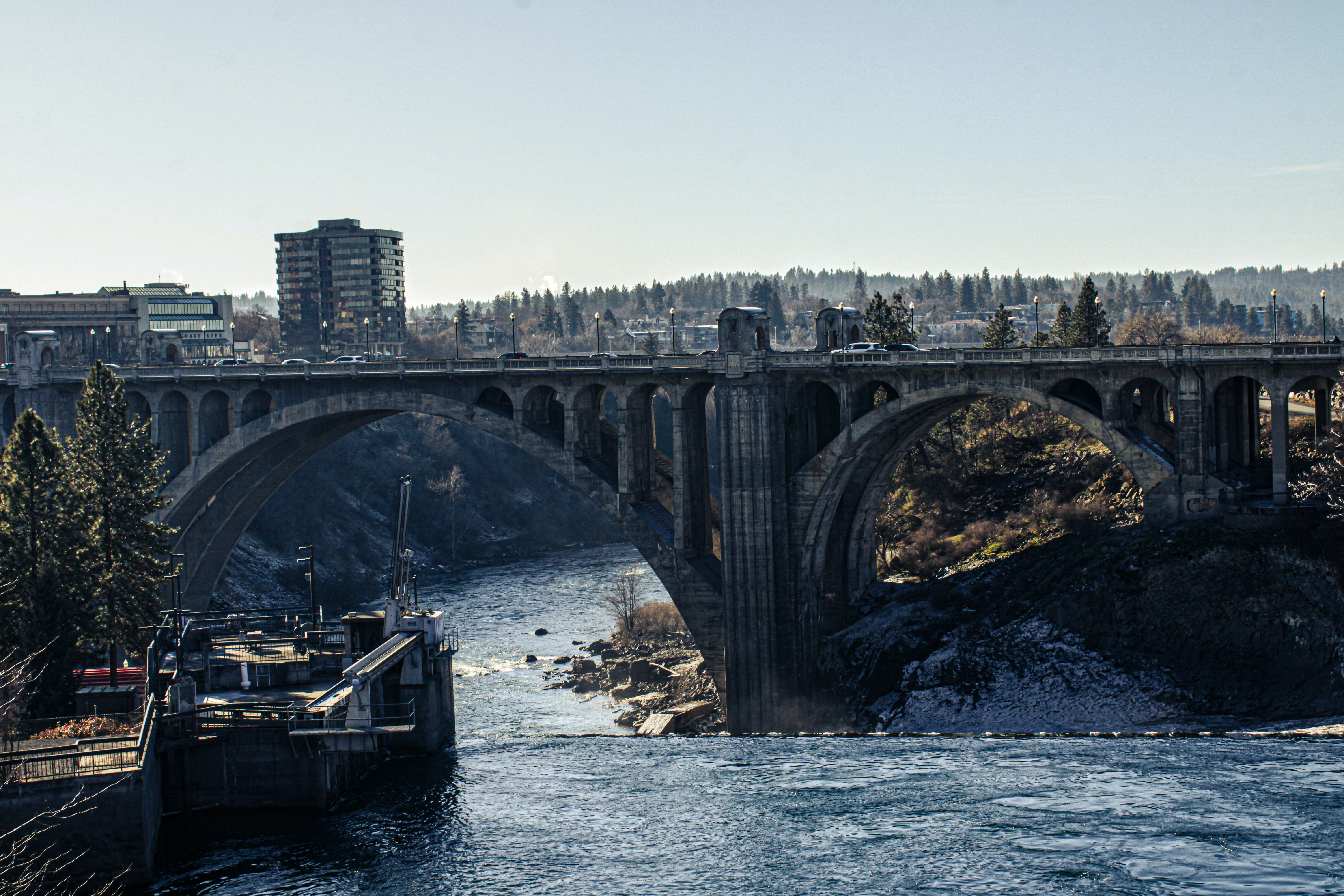 A stone bridge crosses a river in a city.