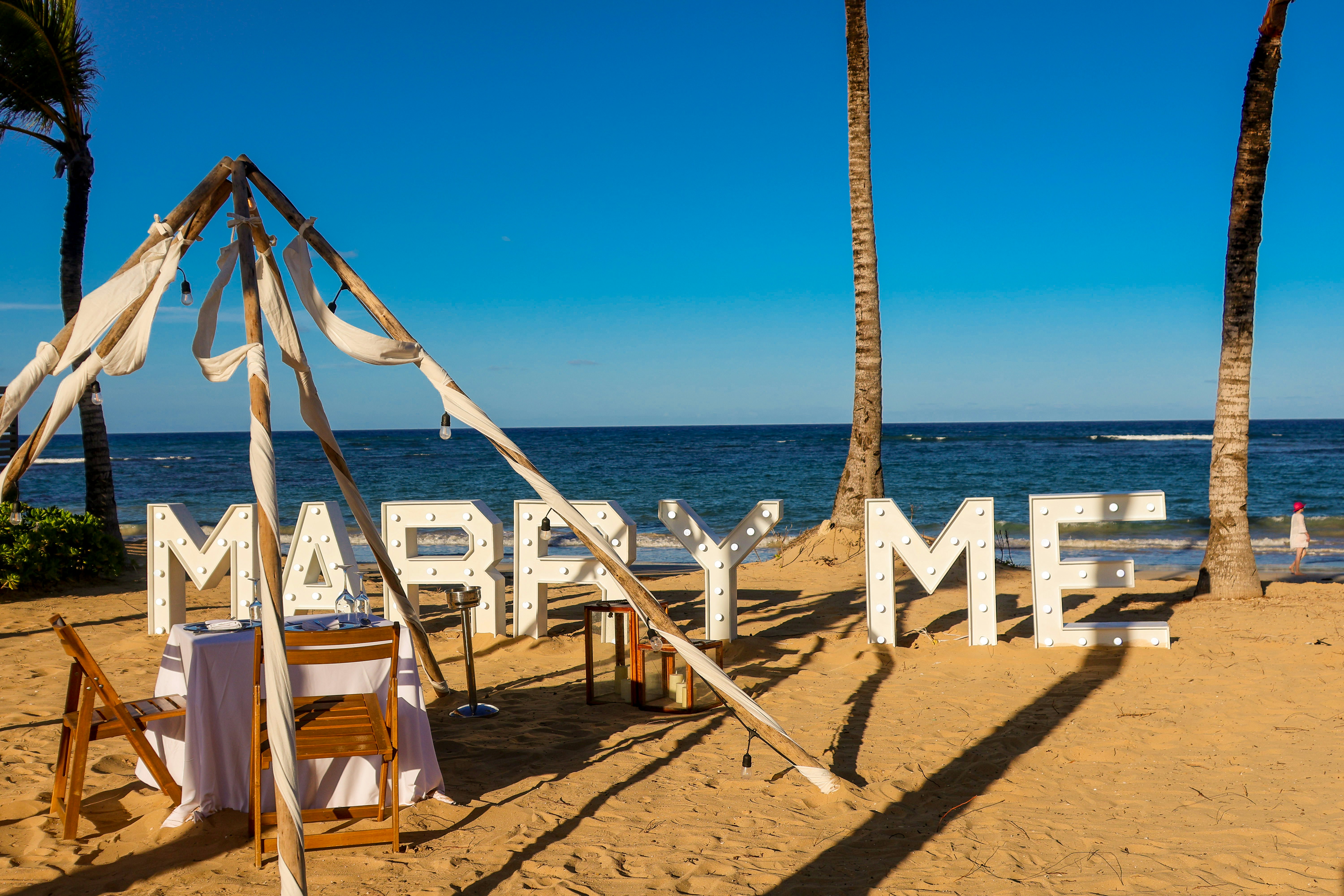 A romantic beach proposal with a "marry me" sign.