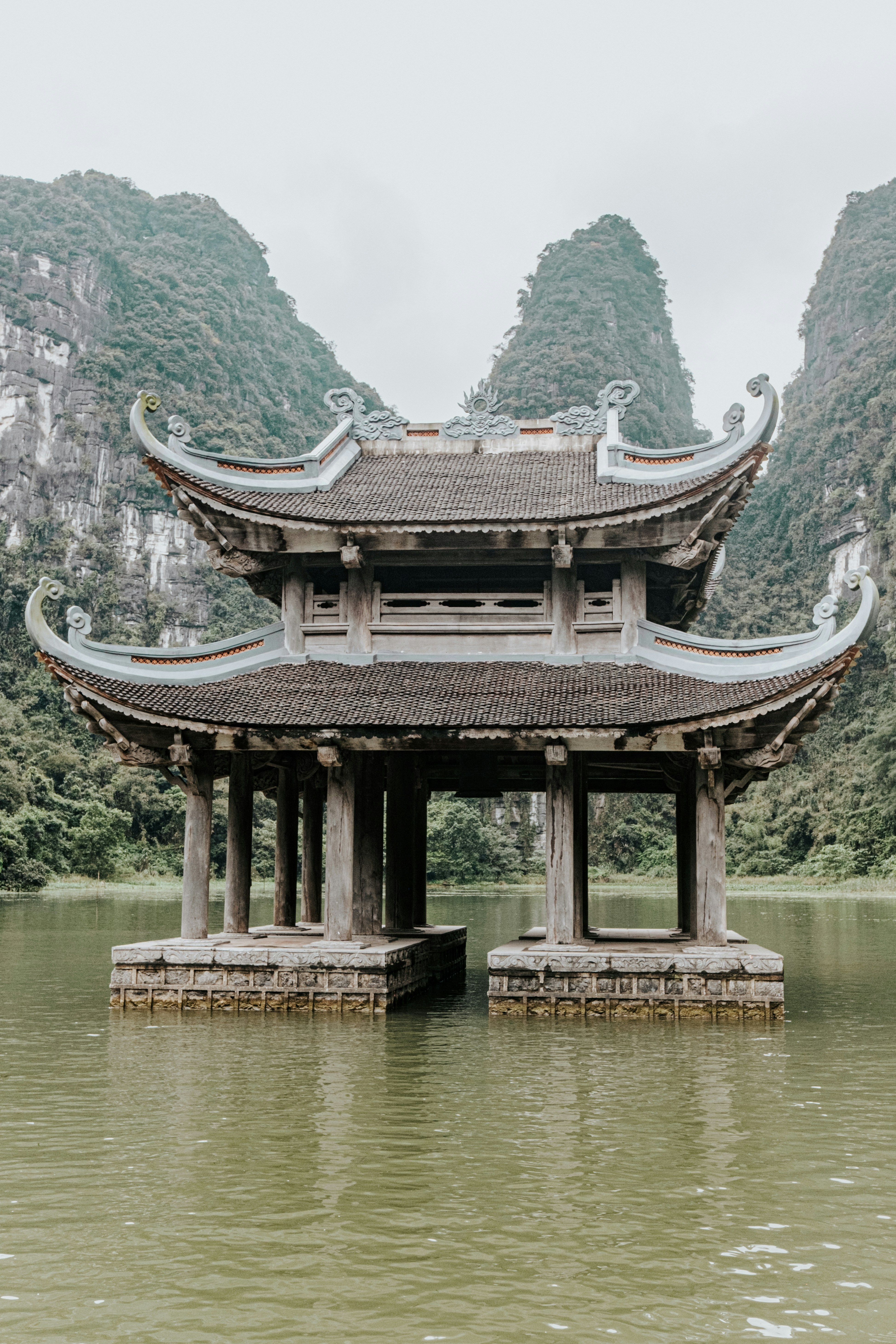 Temple structure surrounded by water and mountains.