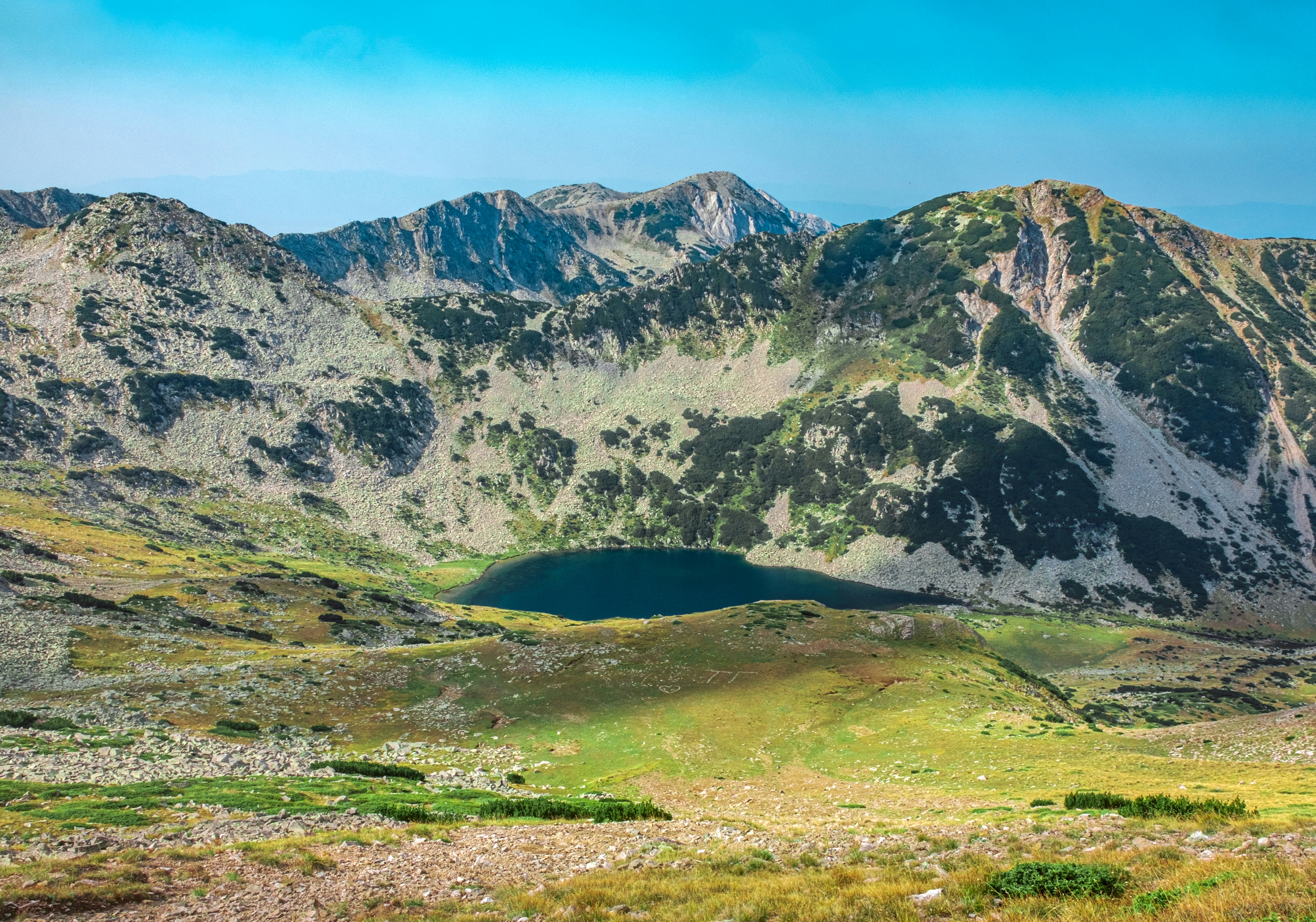 Mountainscape view of lake and grassy field.