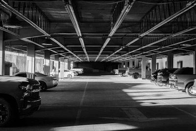 Cars are parked in a long, empty parking garage.