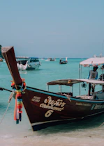 Longtail boats float on the clear, blue ocean.