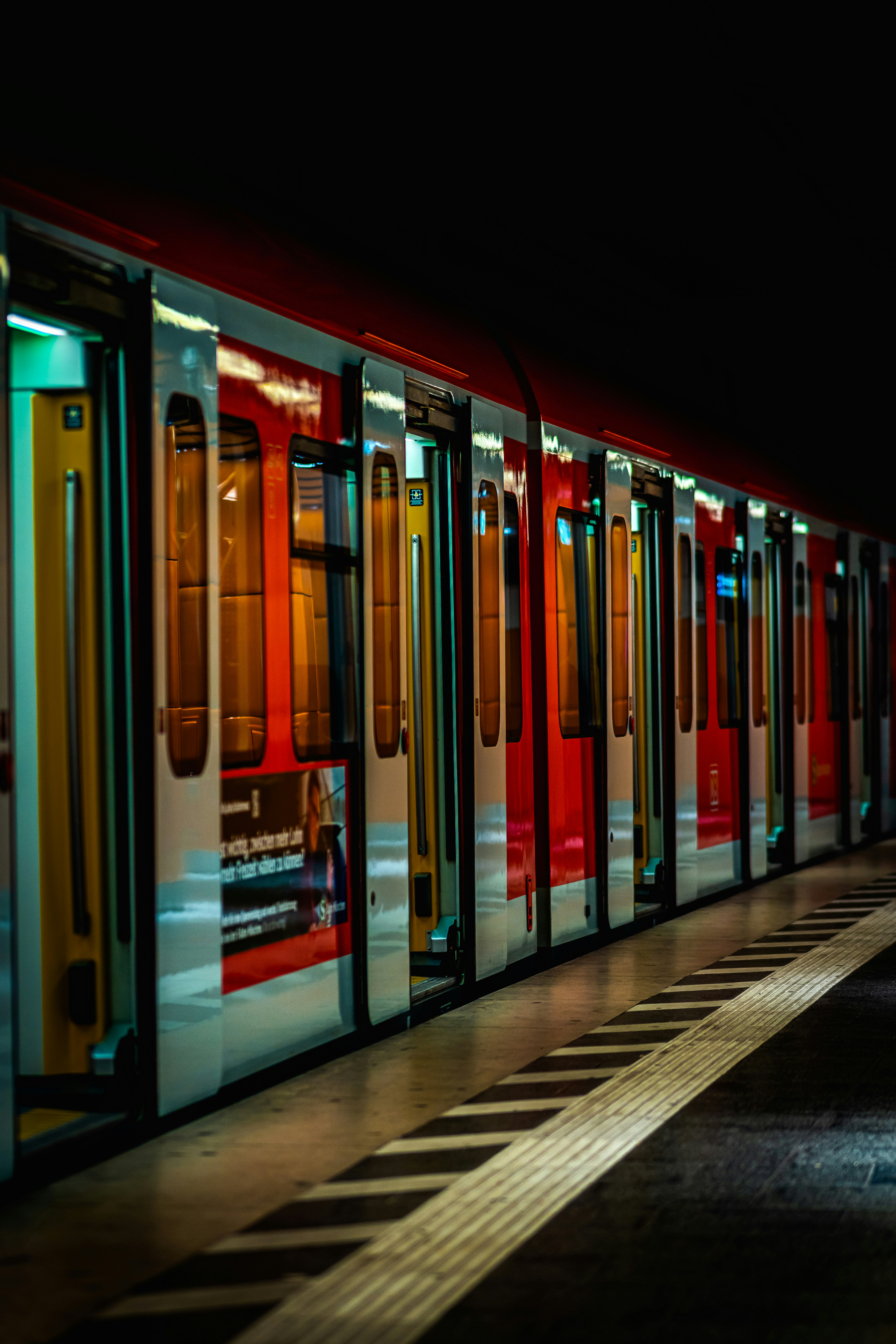 Red train at a station with opened doors.