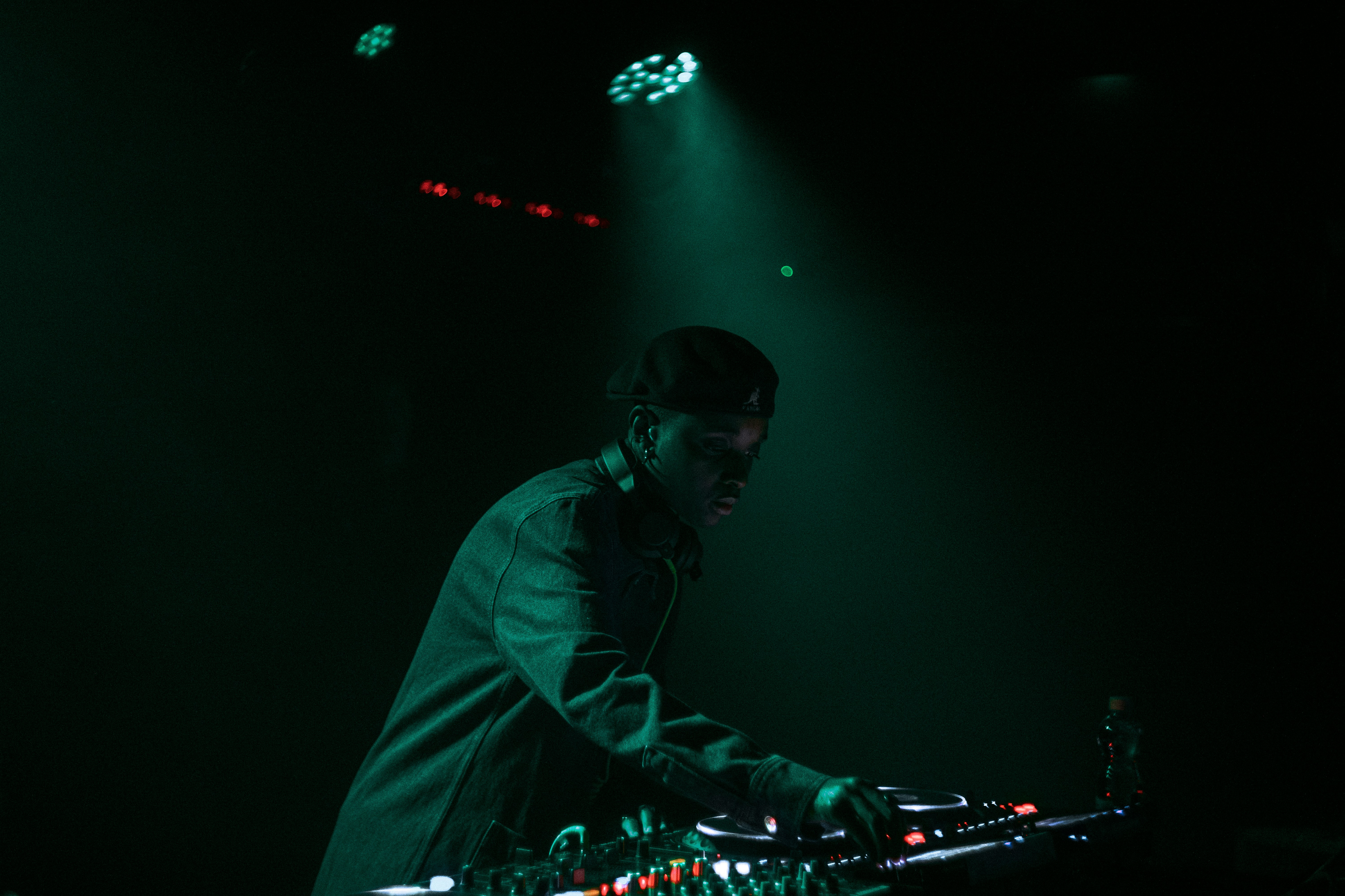 A dj performs in front of green stage lights.