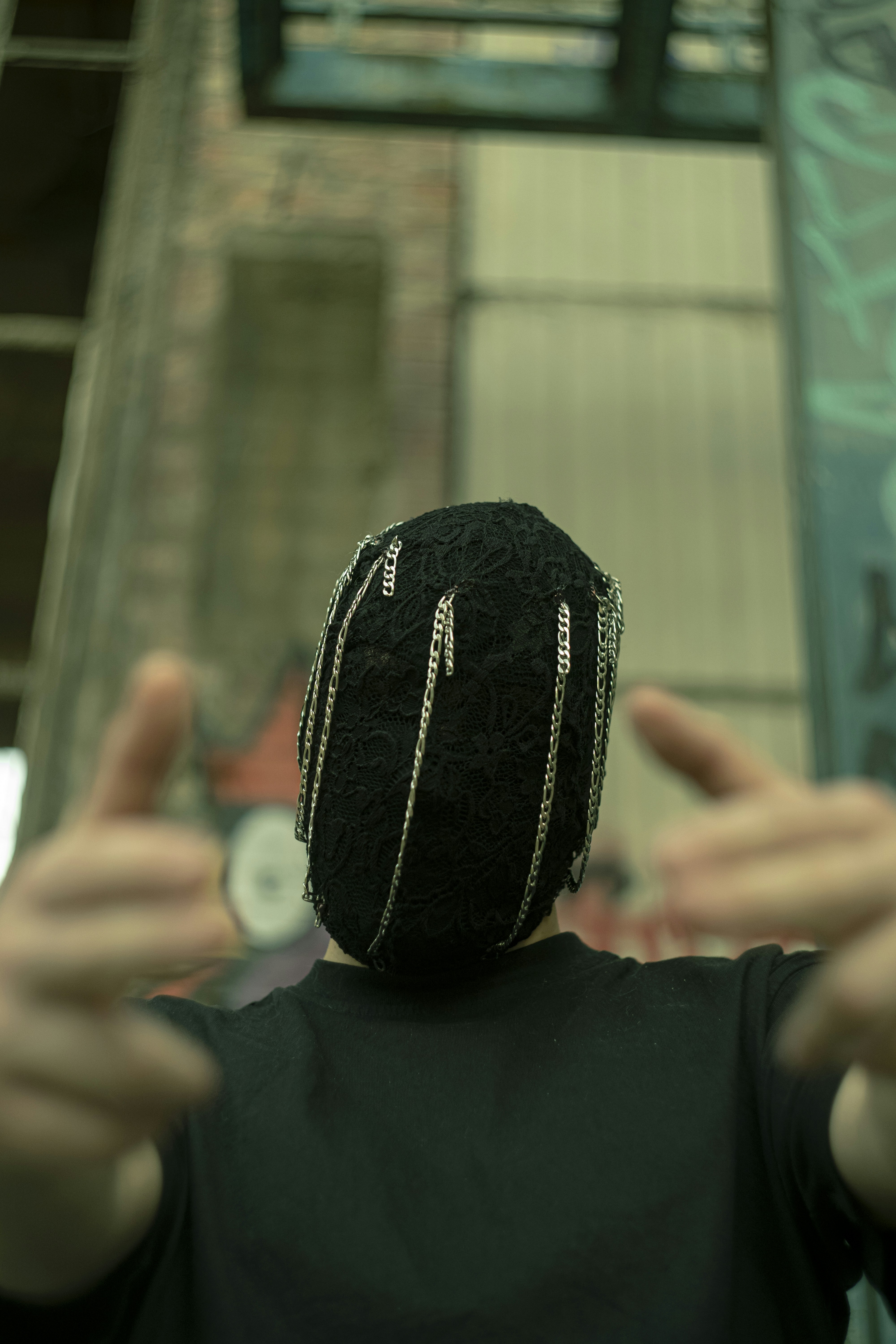 A person wearing a mask poses with their hands up.