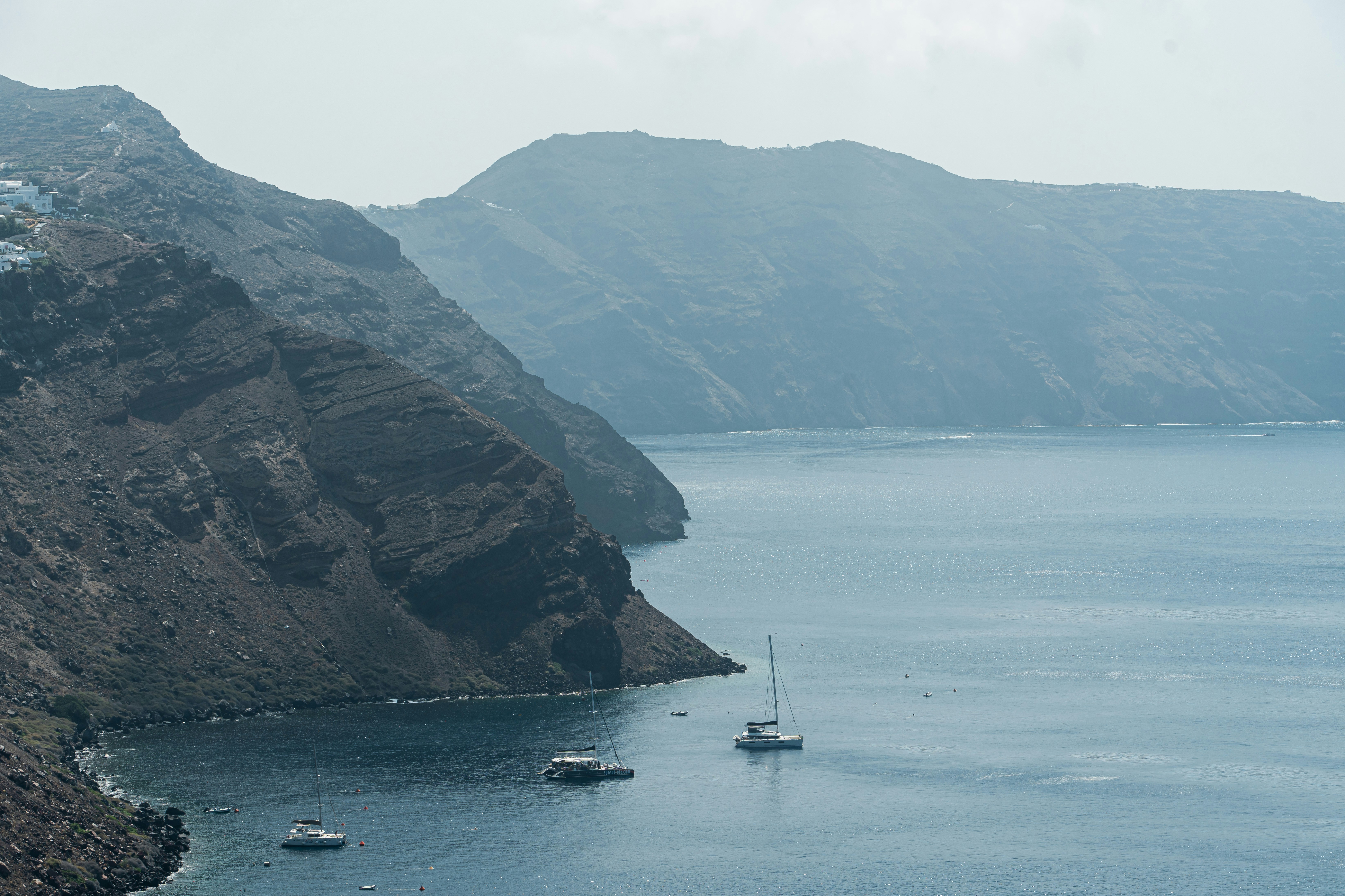 Mountains meet the sea, with boats in the water.