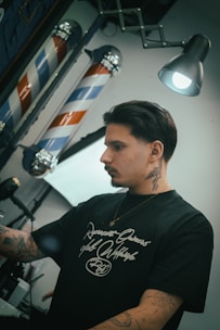 Barber standing near barber poles in a shop.