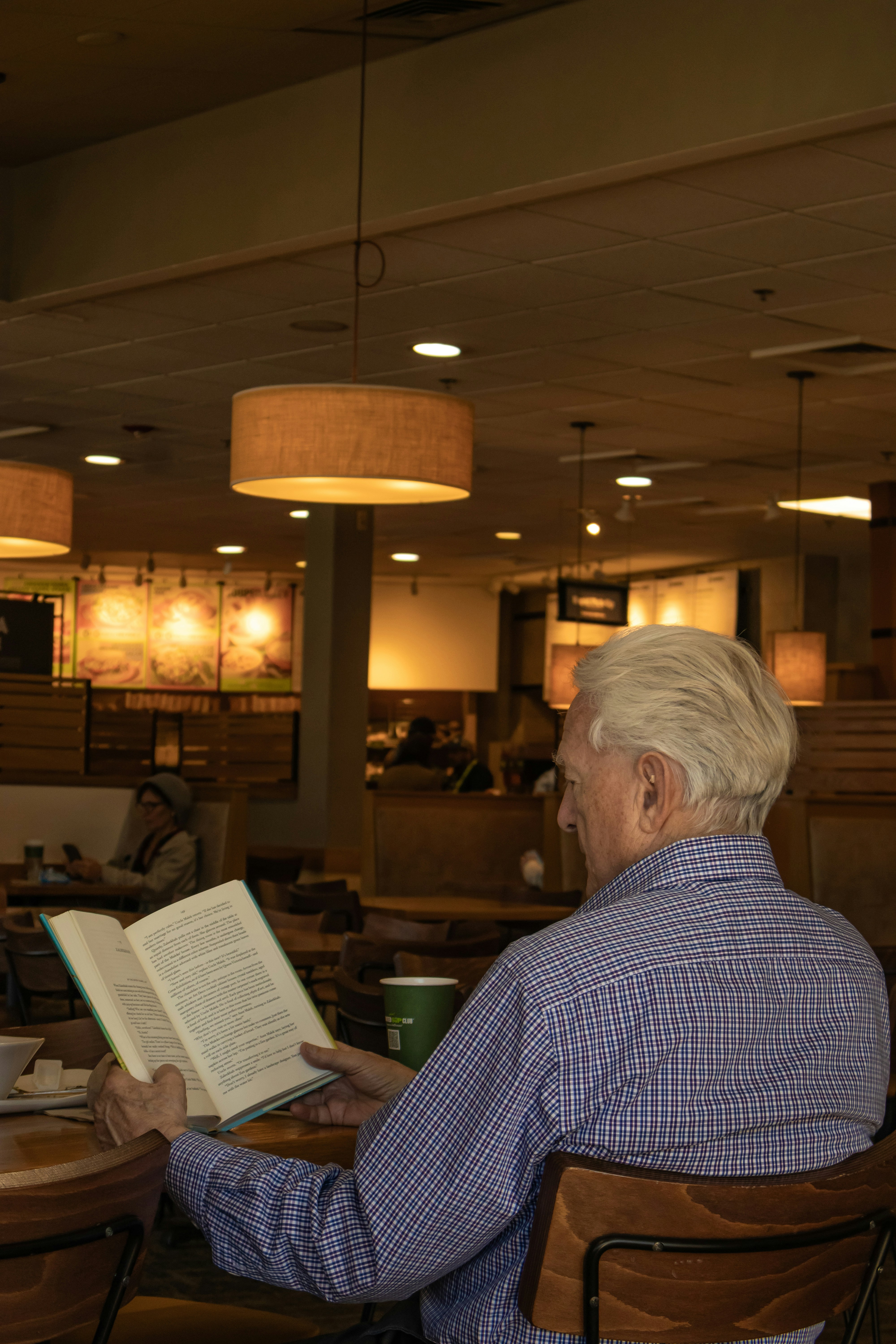 An elderly man is reading a book indoors.