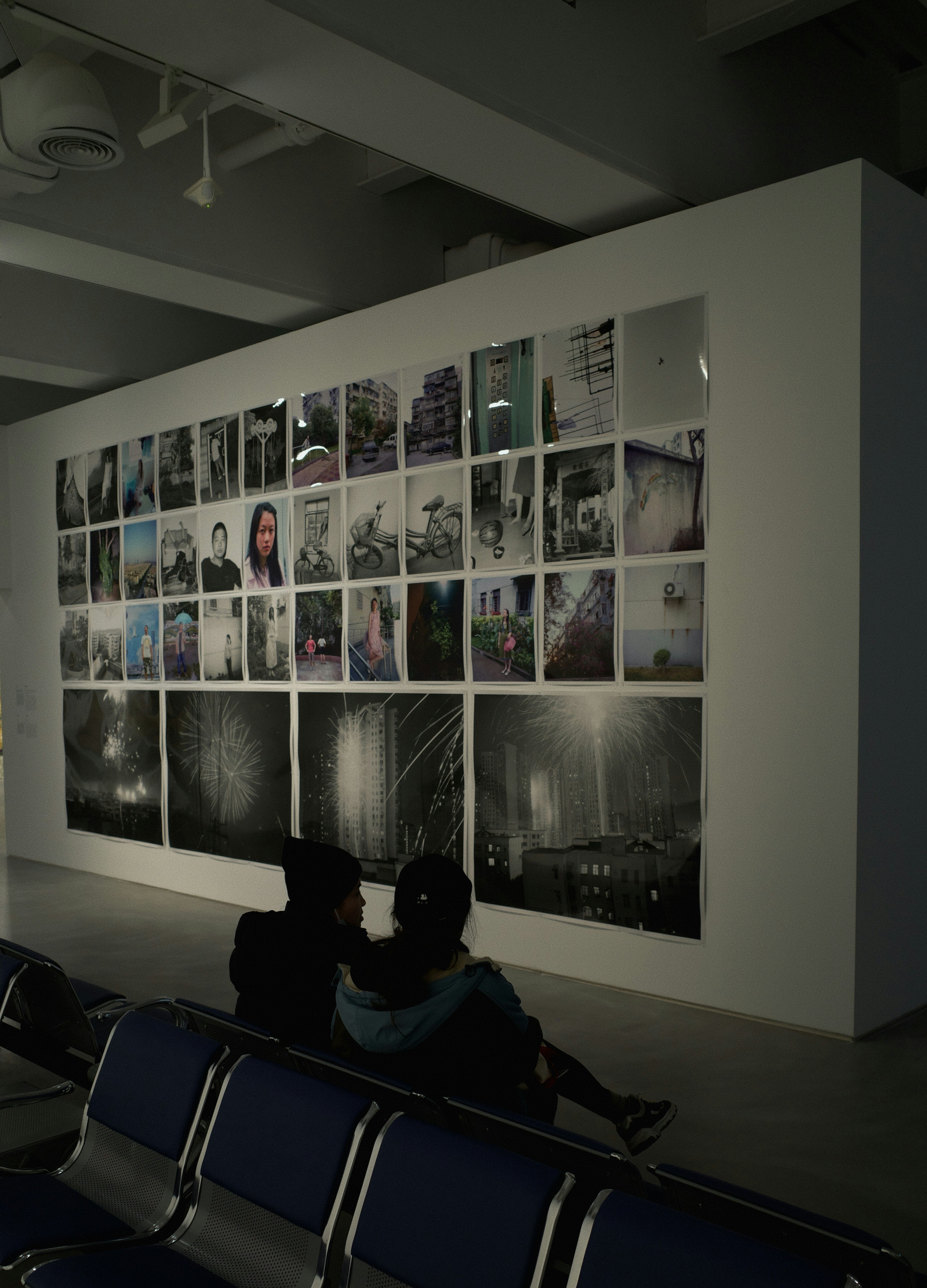 People admire photos on a gallery wall.