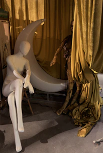 A mannequin sits beside a moon prop.